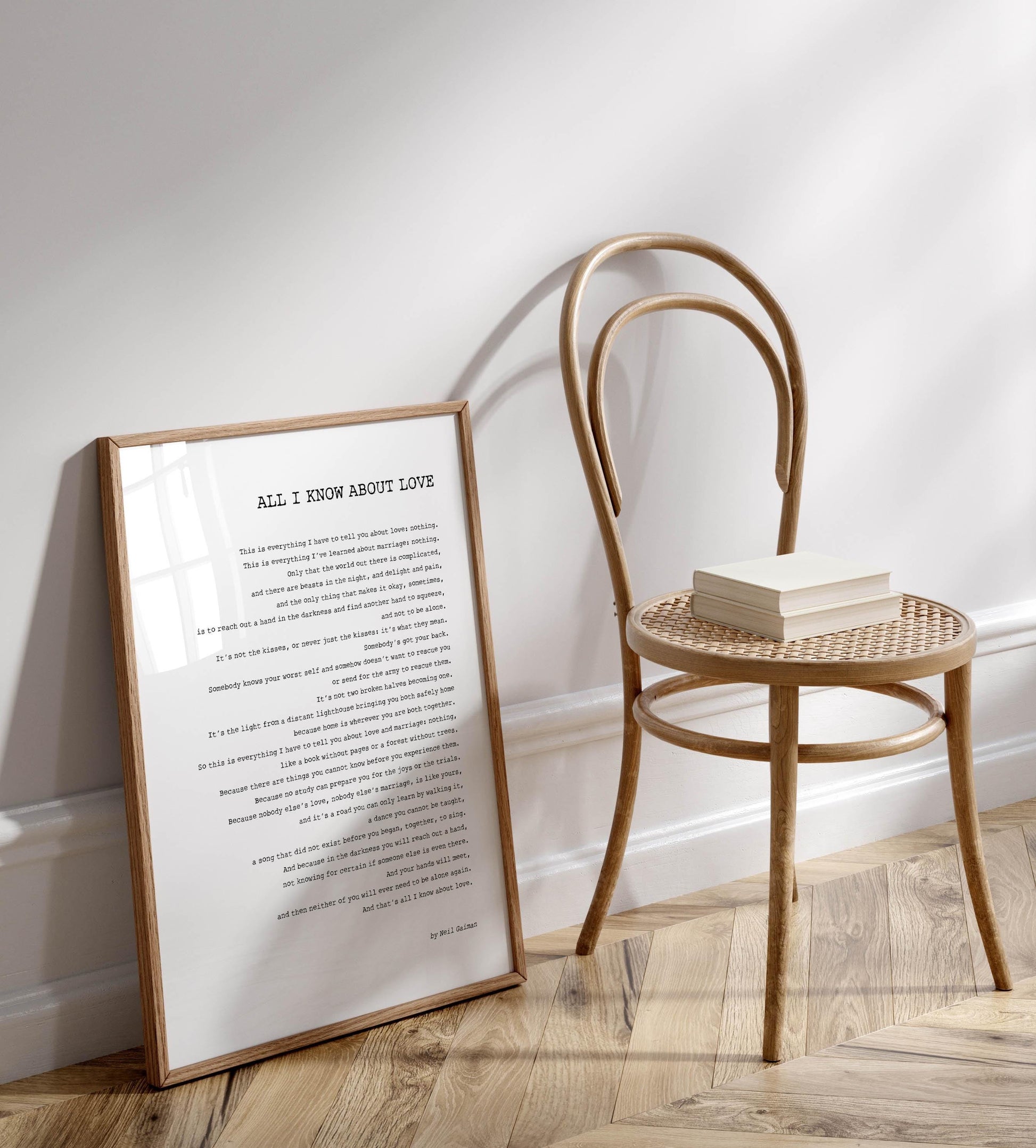 a wooden chair with a book resting on it, positioned next to a framed text that reads "All I know about love".
