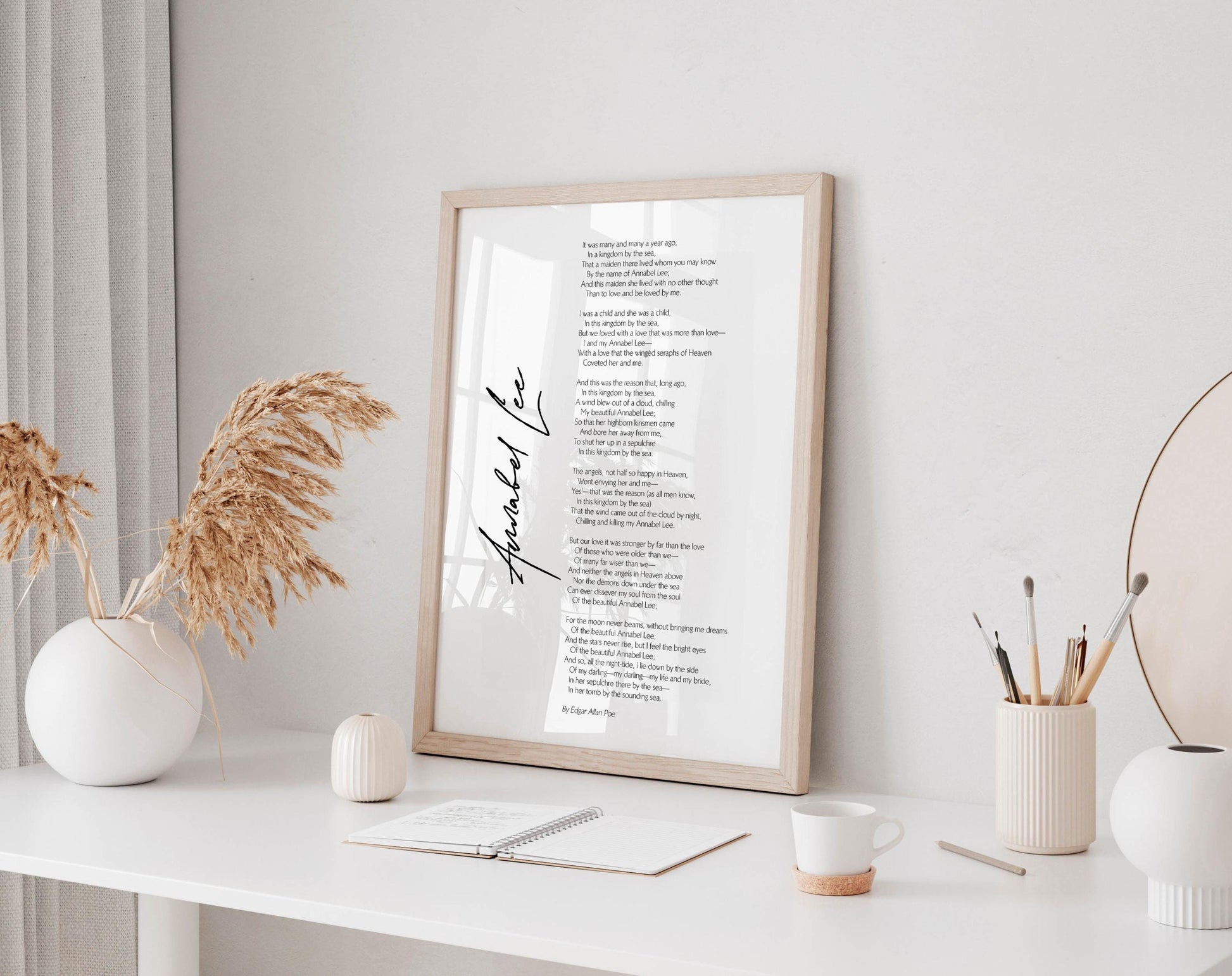 a framed poem titled "Thankful Lee" displayed on a white wall, accompanied by a white desk with various objects such as a notebook, a cup, and a vase.