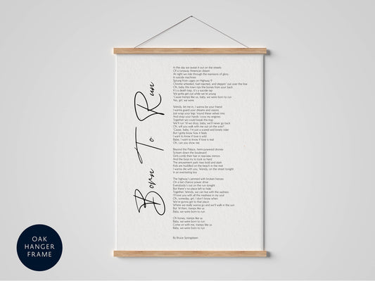 The image is a framed print of a poem titled "Born to Run" by Bruce Springsteen, which is hung on a wall.