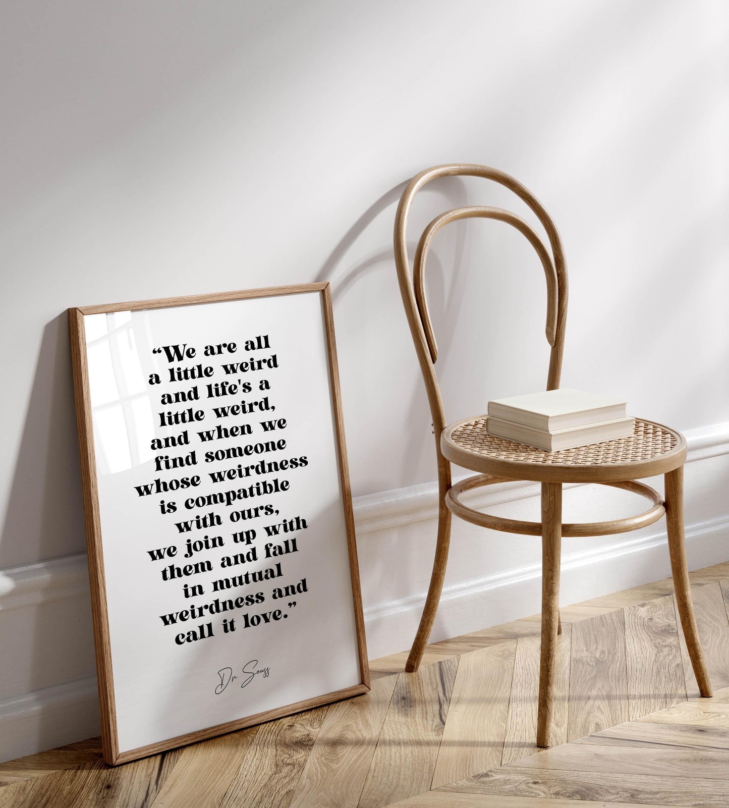 a quote by Dr. Shes on a wall, accompanied by a wooden chair and a book on a wooden floor.