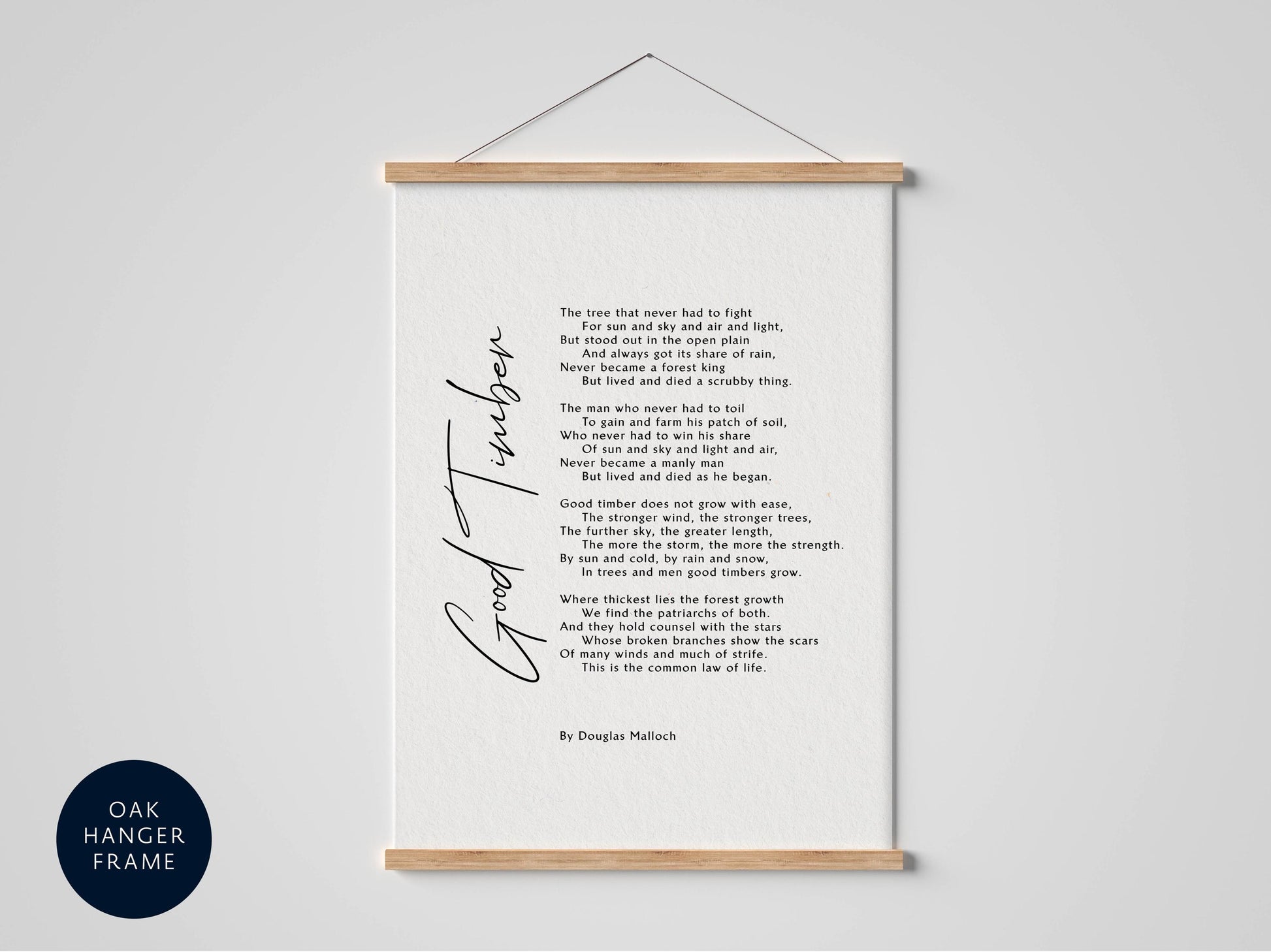 a framed poem titled "Good timber" by Douglas Mallock, which is hung on a wall. The poem is written in a cursive font and features a wooden frame. The text is written in black ink on a white background, and the image includes a blue circle with the text "OAK HANGER FRAME" in the bottom left corner.