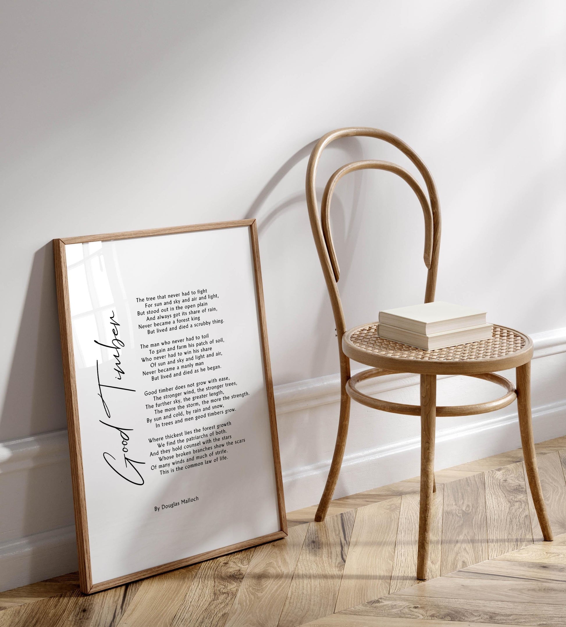 a framed poem titled "The tree that never had to fight" by Douglas Nolich, placed on a wooden floor next to a wooden chair.