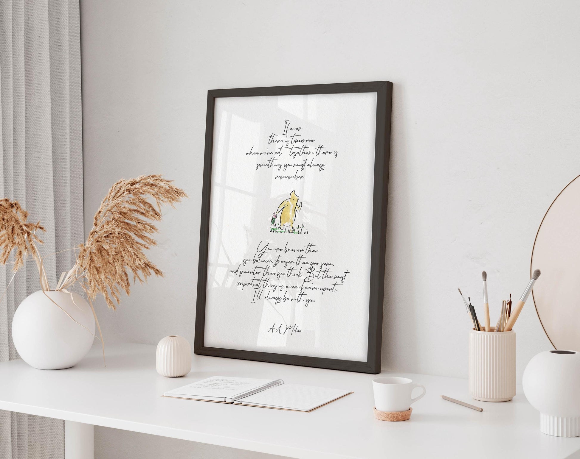 a framed quote with a yellow duck on a white desk, surrounded by various office supplies and decor items.