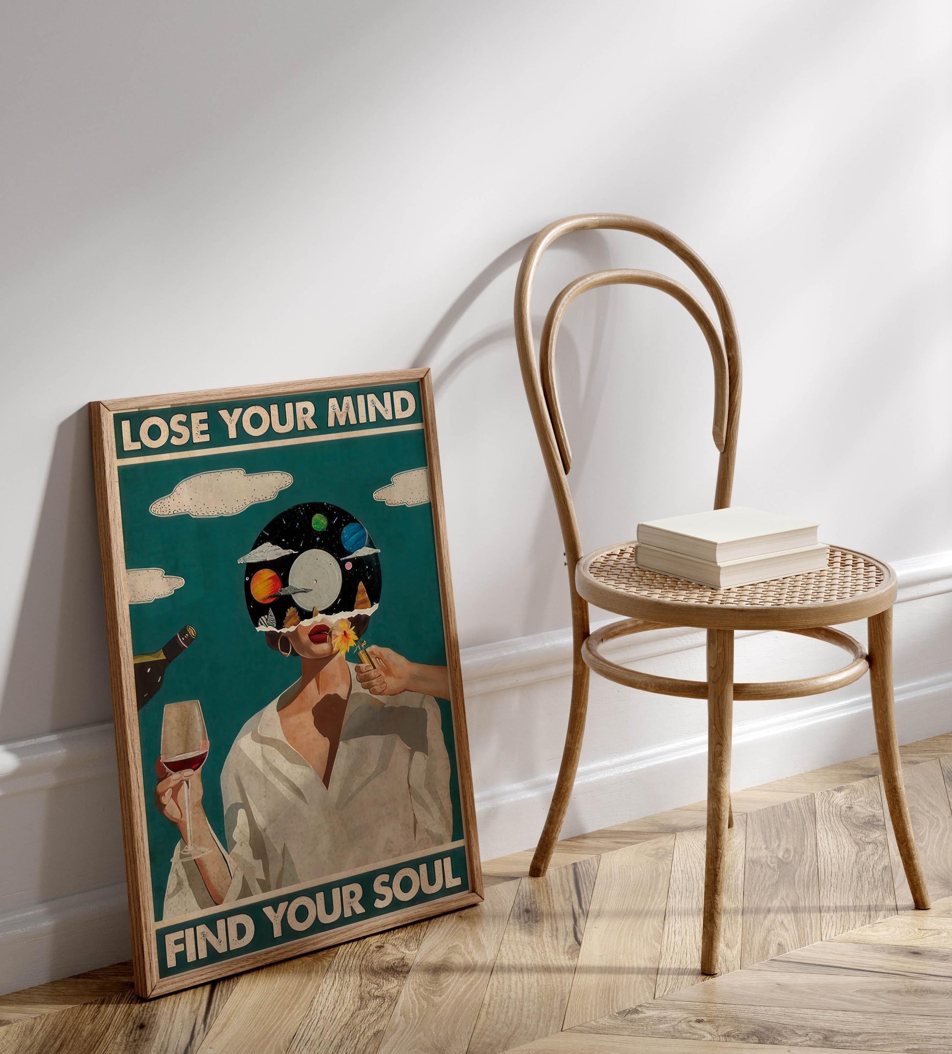 a framed poster with the text "LOSE YOUR MIND FIND YOUR SOUL" and an illustration of a person with a head full of planets. The poster is leaning against a wall, and there is a wooden chair next to it.