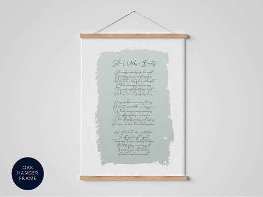 a framed poster with a light blue background and cursive text, hanging on a white wall.
