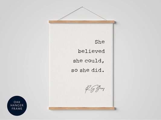 A framed quote by R.S. Grey hangs on a white wall, reading "She believed she could, so she did."