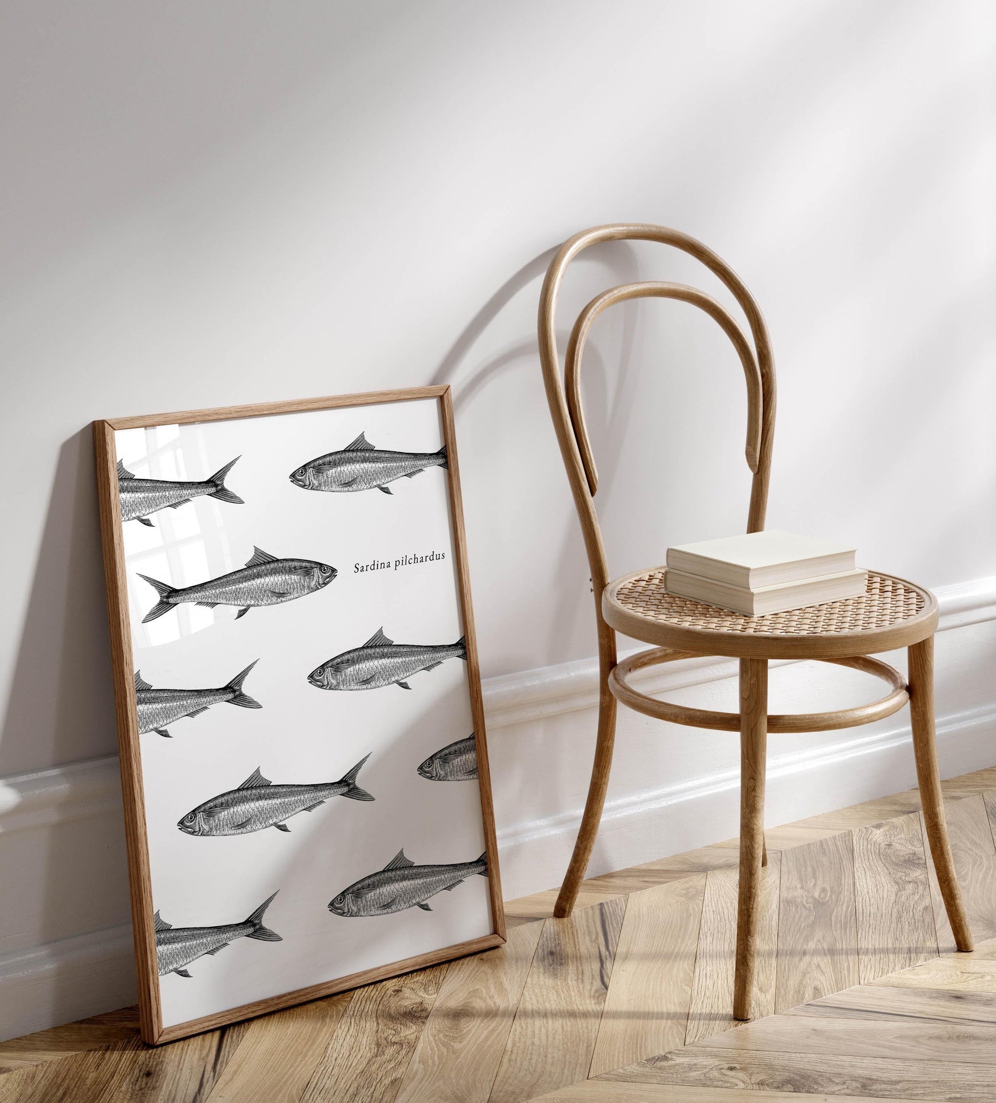 a framed print of fish on a wall, with a wooden chair and a stack of books placed next to it.