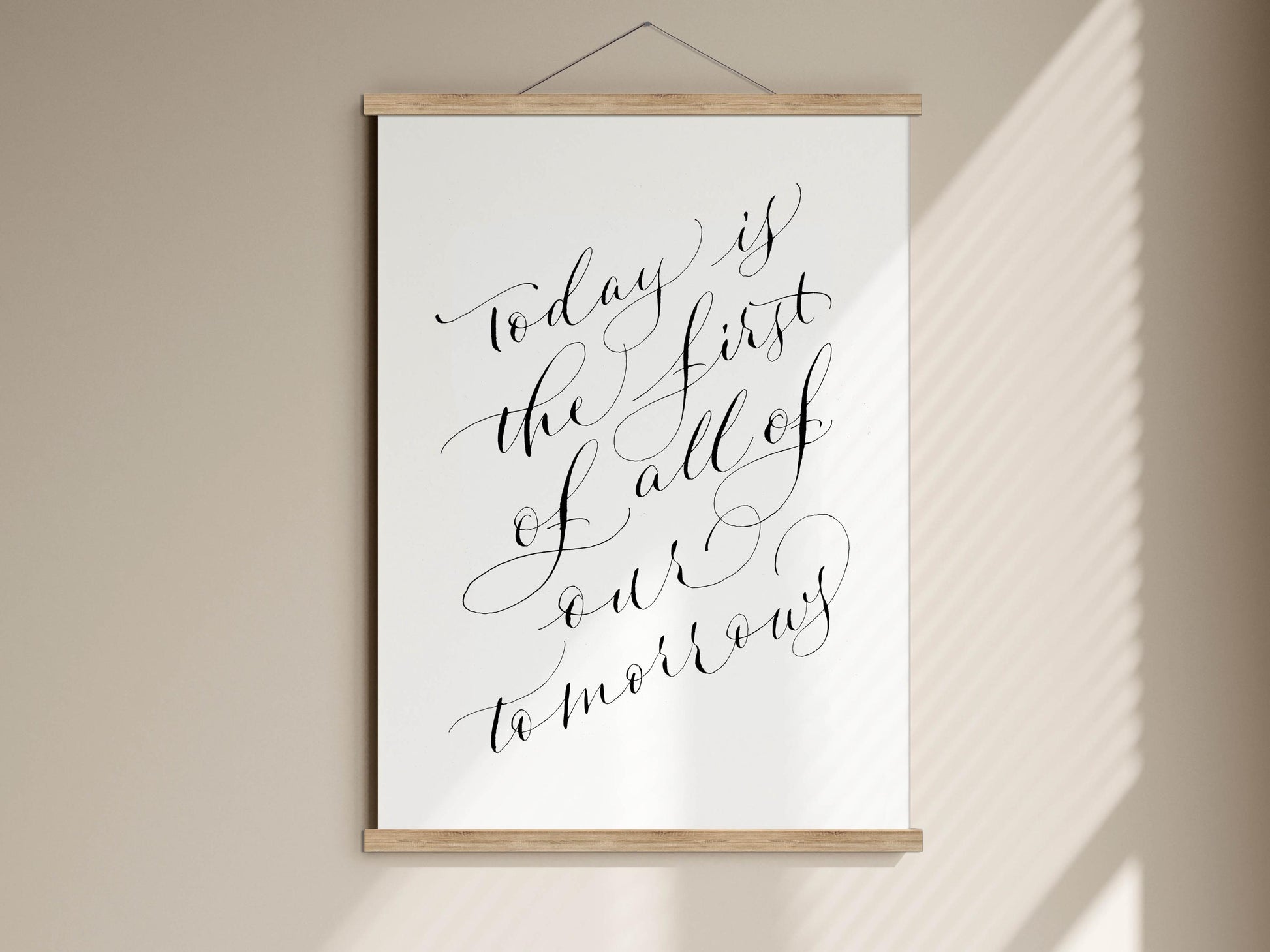a framed print with the text "Today is the first of all of our tomorrow" written in an elegant cursive font.