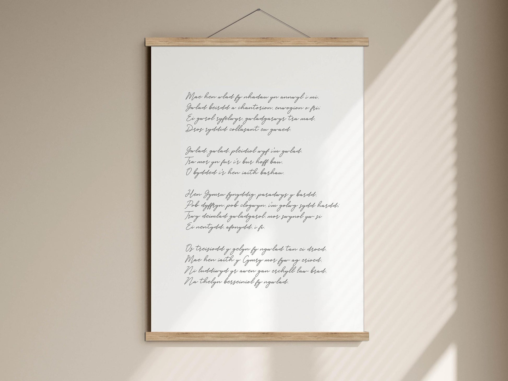a white poster with black text, hanging on a wall. The text appears to be a poem or a song lyrics, written in a cursive or script font. The poster is mounted on a wooden frame, which is hanging on the wall. The image does not contain any additional objects or text that can be described in detail.