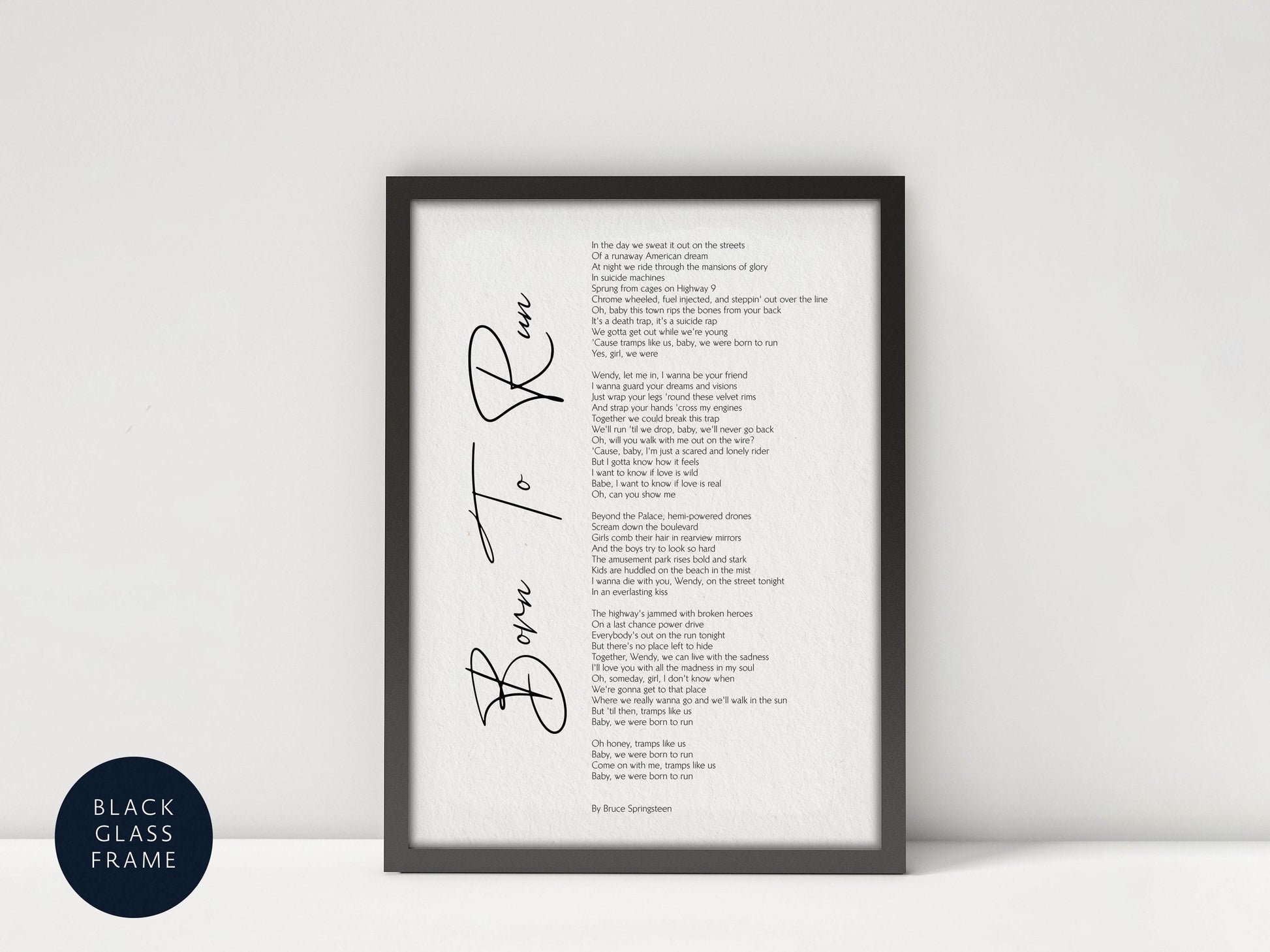 a framed black and white photograph of a poem titled "Born to Run" by Bruce Davidson. The poem is written in a cursive font and is framed in a black frame. The text is displayed in a clean, white background, and the image is described as a "collage of multiple images" and "a black and white photograph of a poem."