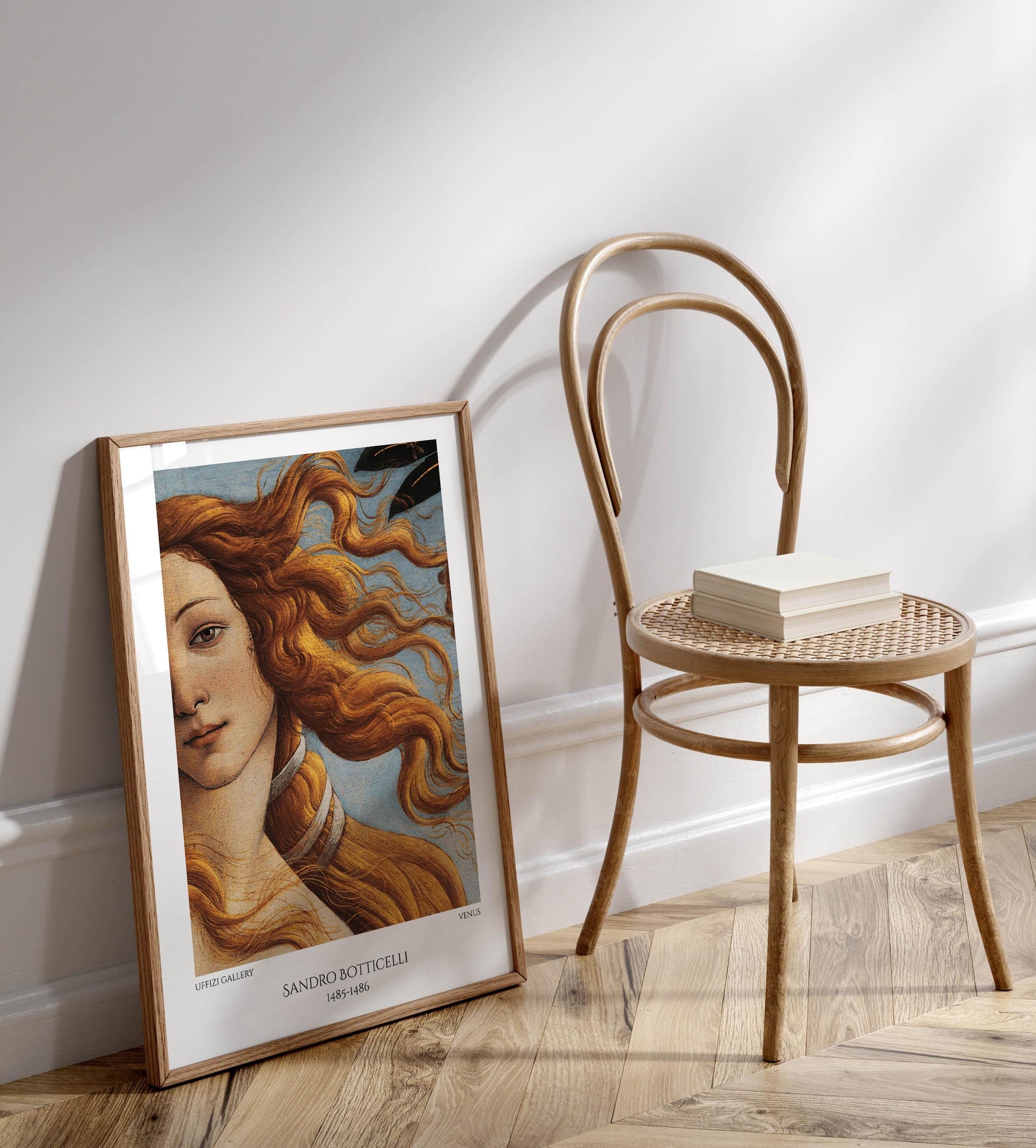 a framed painting of a woman with flowing hair, placed on a wooden floor next to a wooden chair.