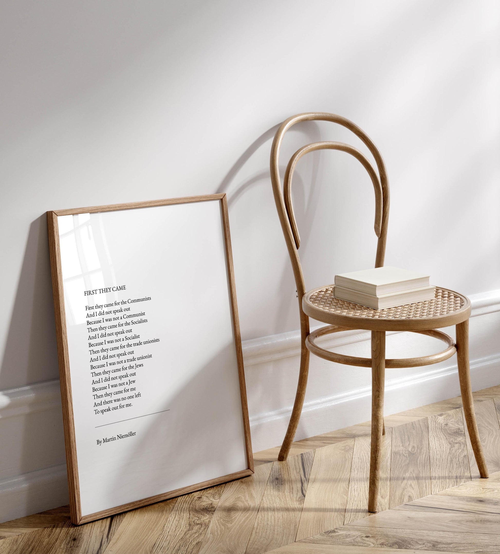 a framed poem titled "First they came to the Commons" by Martin Simoner, placed on a wooden floor next to a wooden chair.