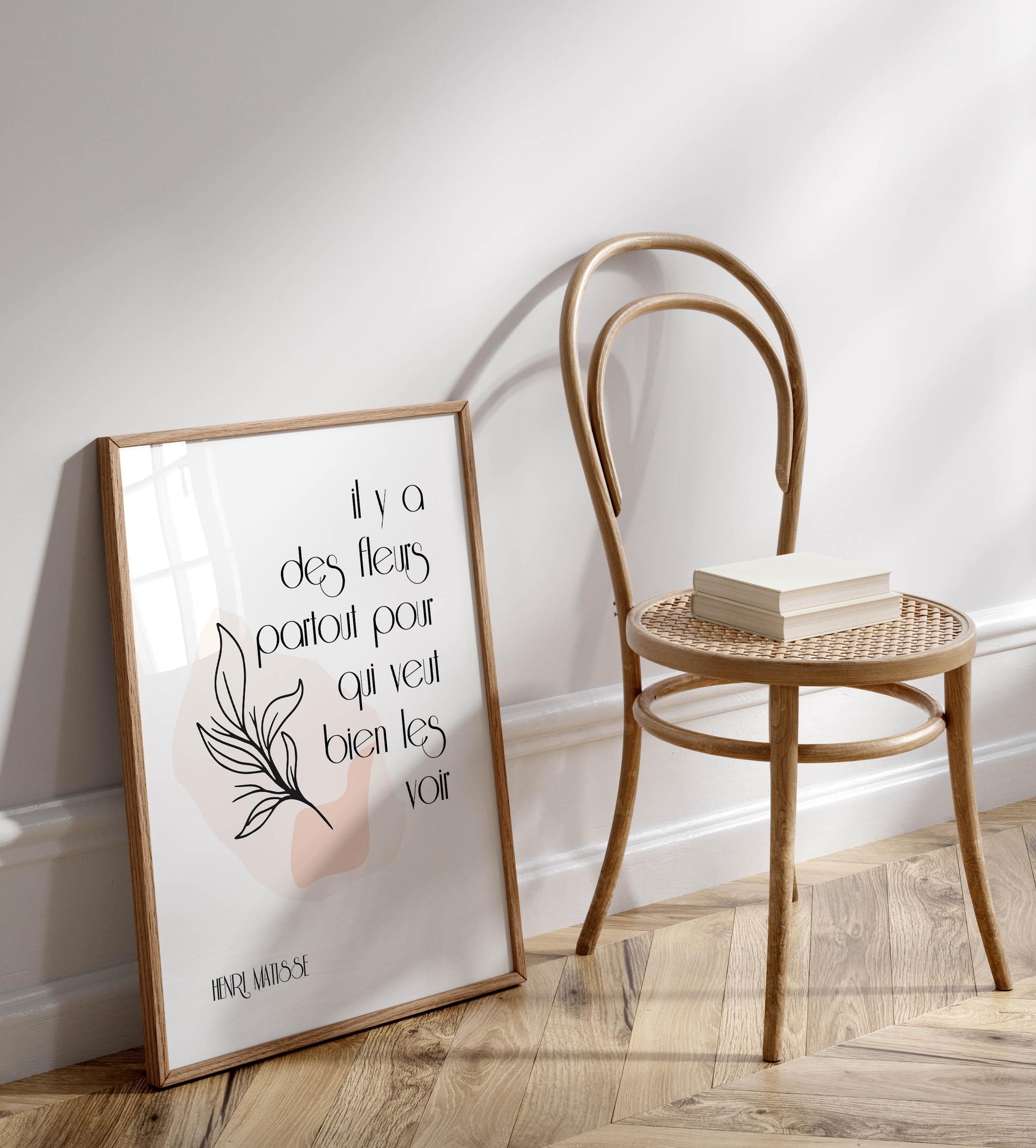 a framed poster with a quote on it, placed next to a wooden chair on a wooden floor.