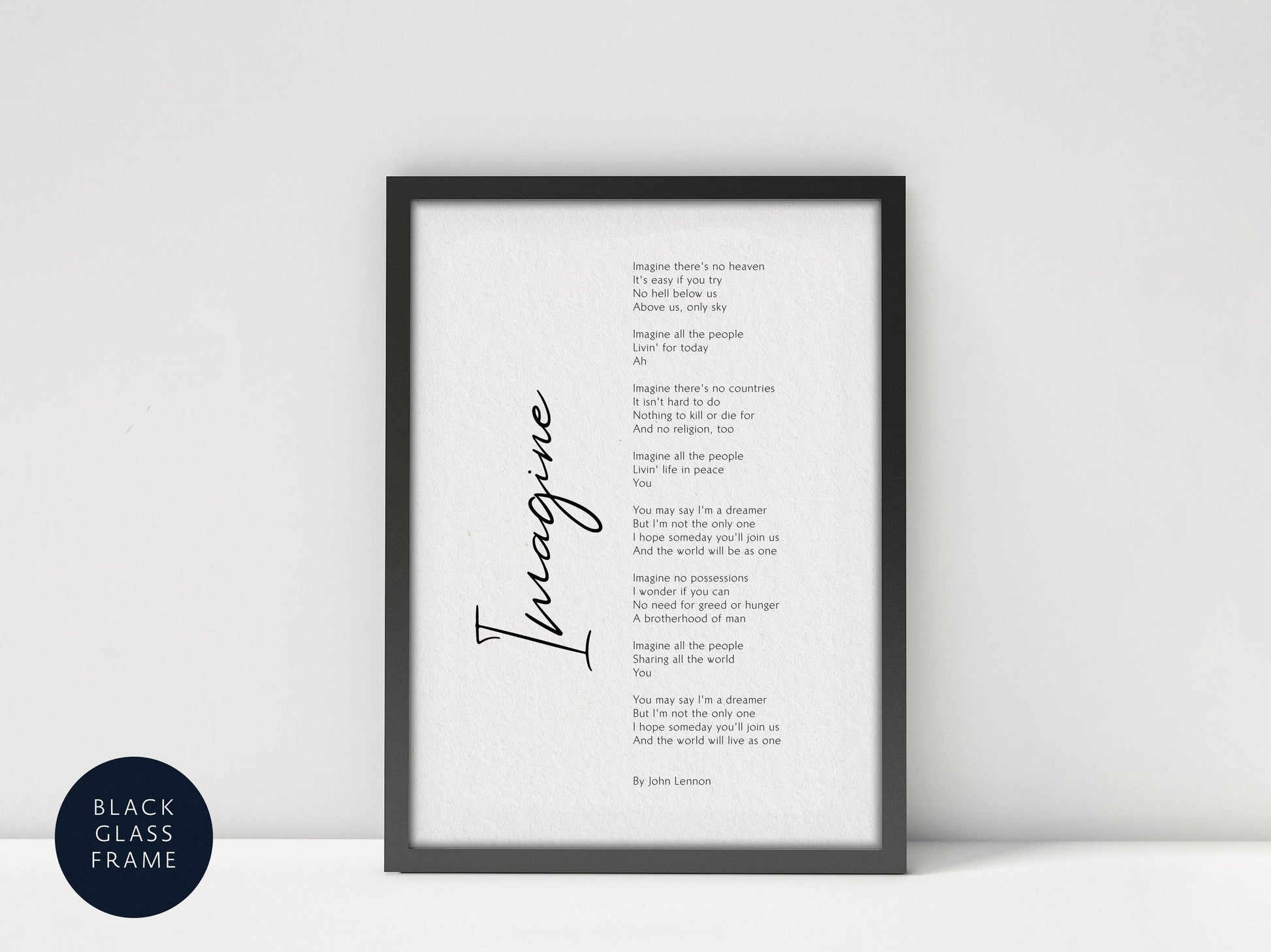 a framed black and white poem titled "Imagine" by John Lennon, which is displayed on a white wall.