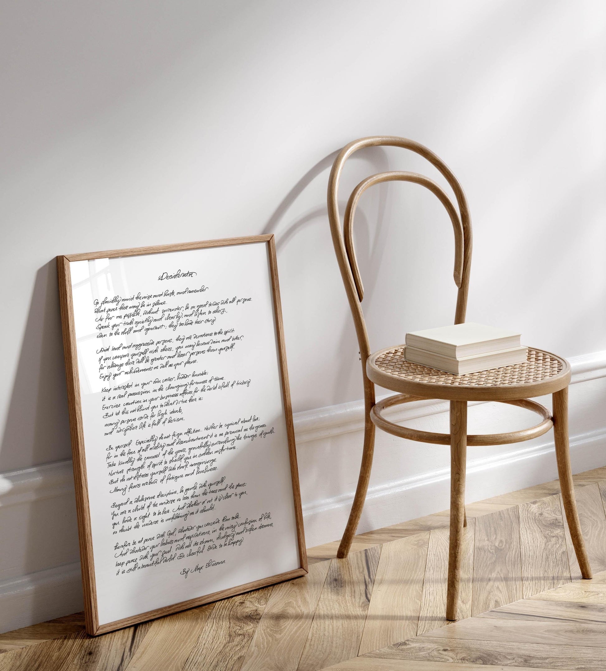 a wooden chair with a book resting on it, positioned next to a framed handwritten poem on a wall.