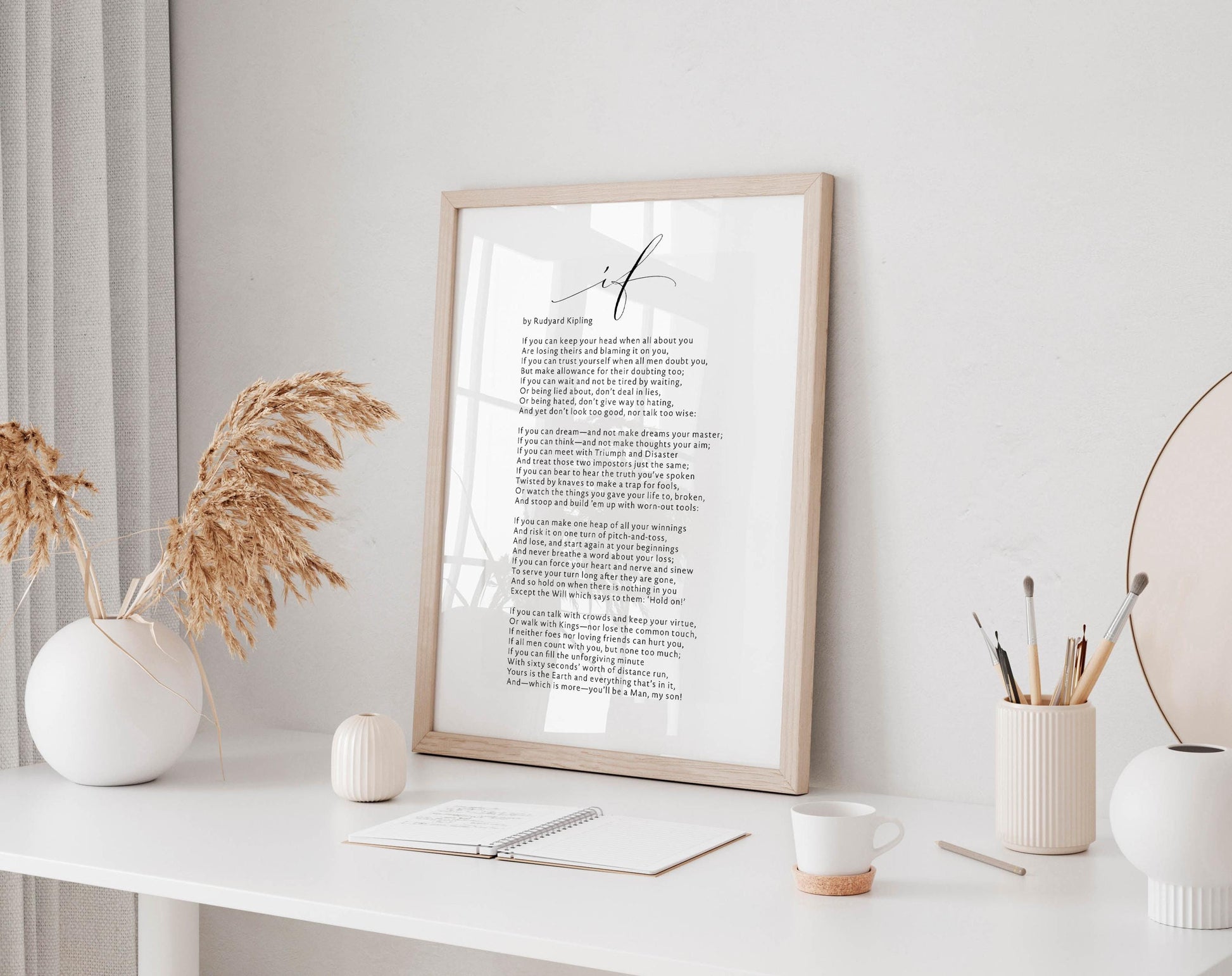 a framed poem titled "I am" displayed on a white desk, accompanied by a notebook, a cup, and a vase with dried flowers.