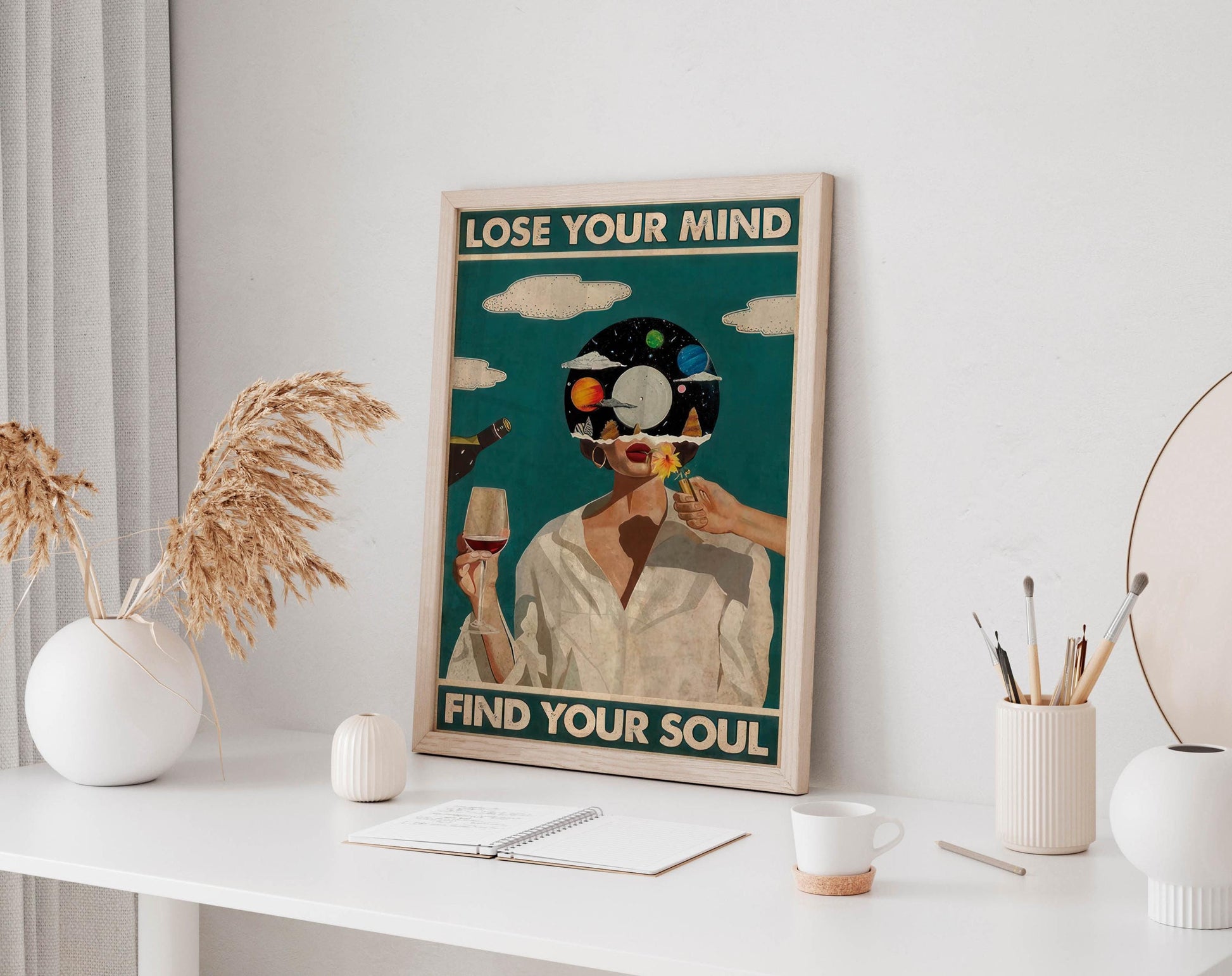 a framed poster with the text "LOSE YOUR MIND FIND YOUR SOUL" displayed on a white desk. The poster also includes an illustration of a woman with a cosmic background. The desk has various items on it, such as a notebook, a cup, and a vase.