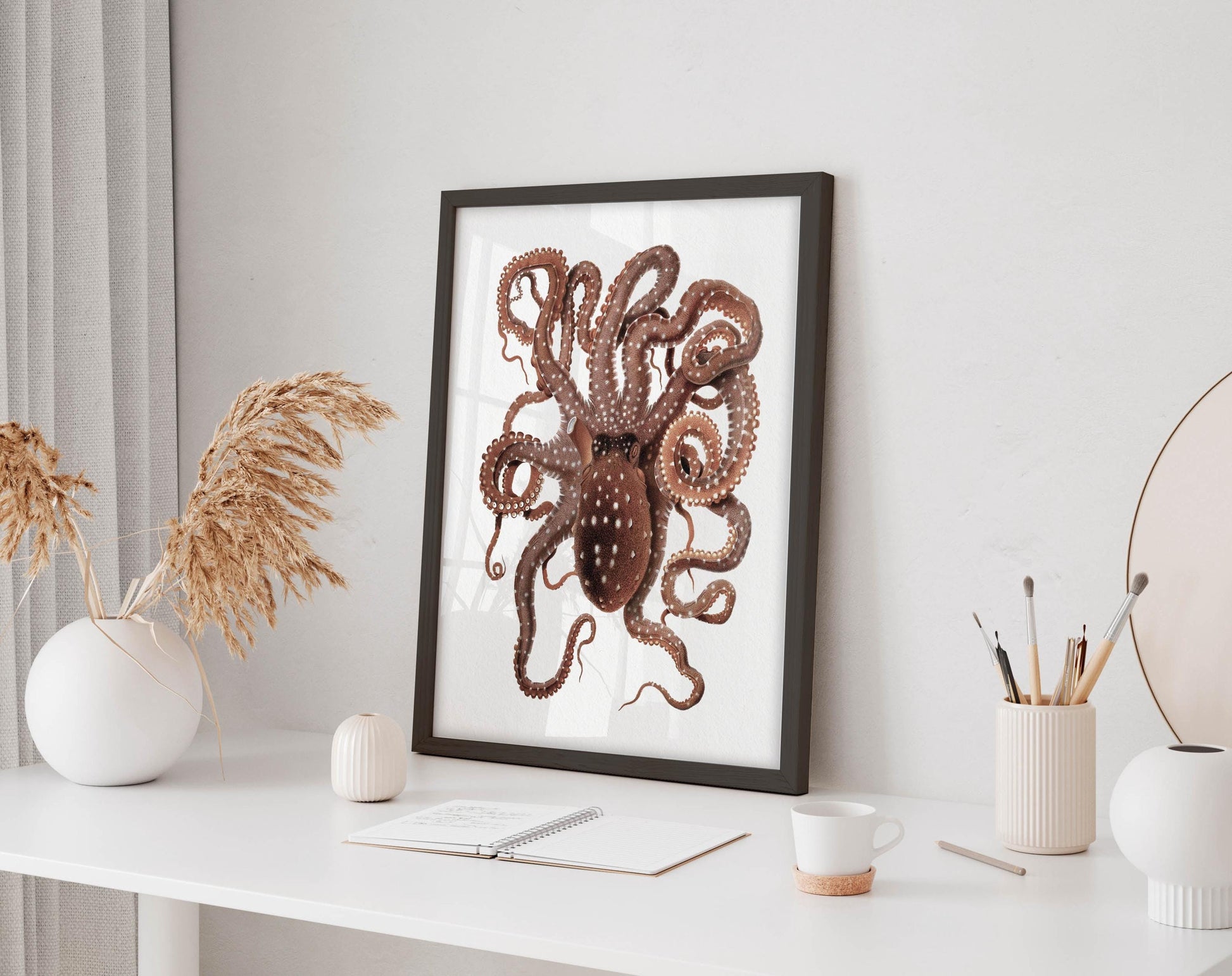 a framed illustration of an octopus on a white desk, accompanied by various office supplies and decorative items.