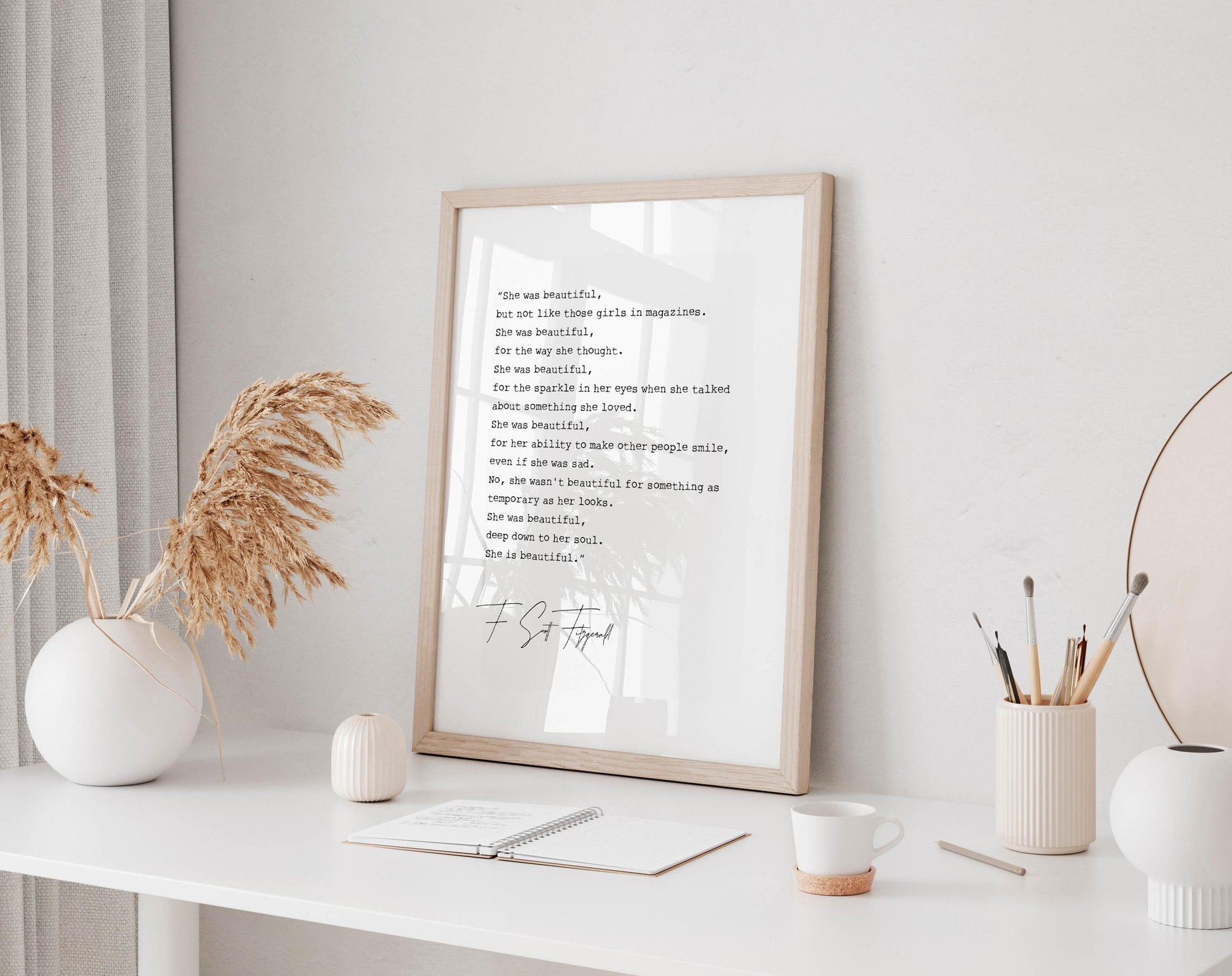 a framed quote on a white shelf, surrounded by various objects such as a notebook, a cup, and a vase with dried flowers.
