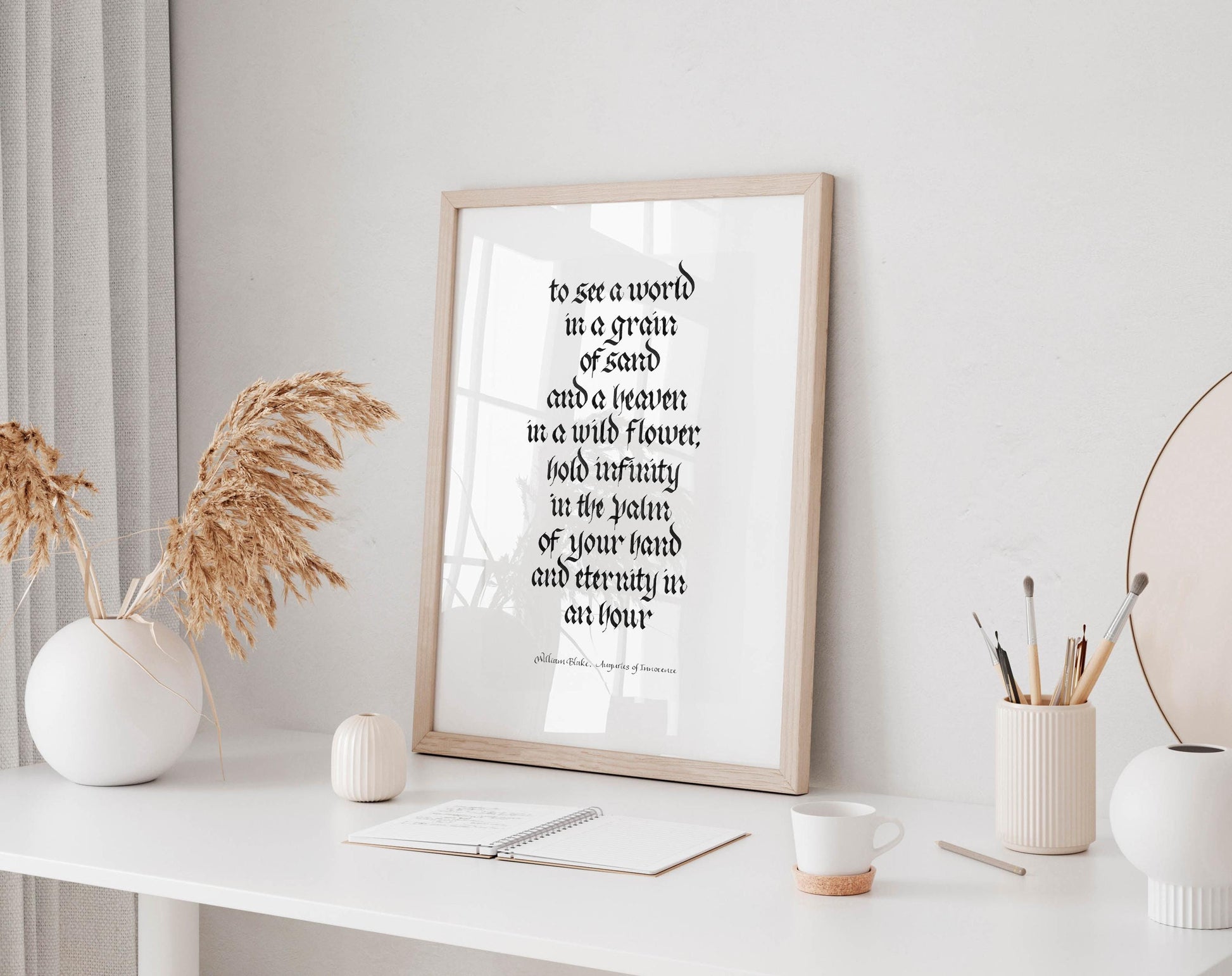 a framed quote on a white shelf, surrounded by various objects such as a notebook, a cup, and a vase with dried flowers.