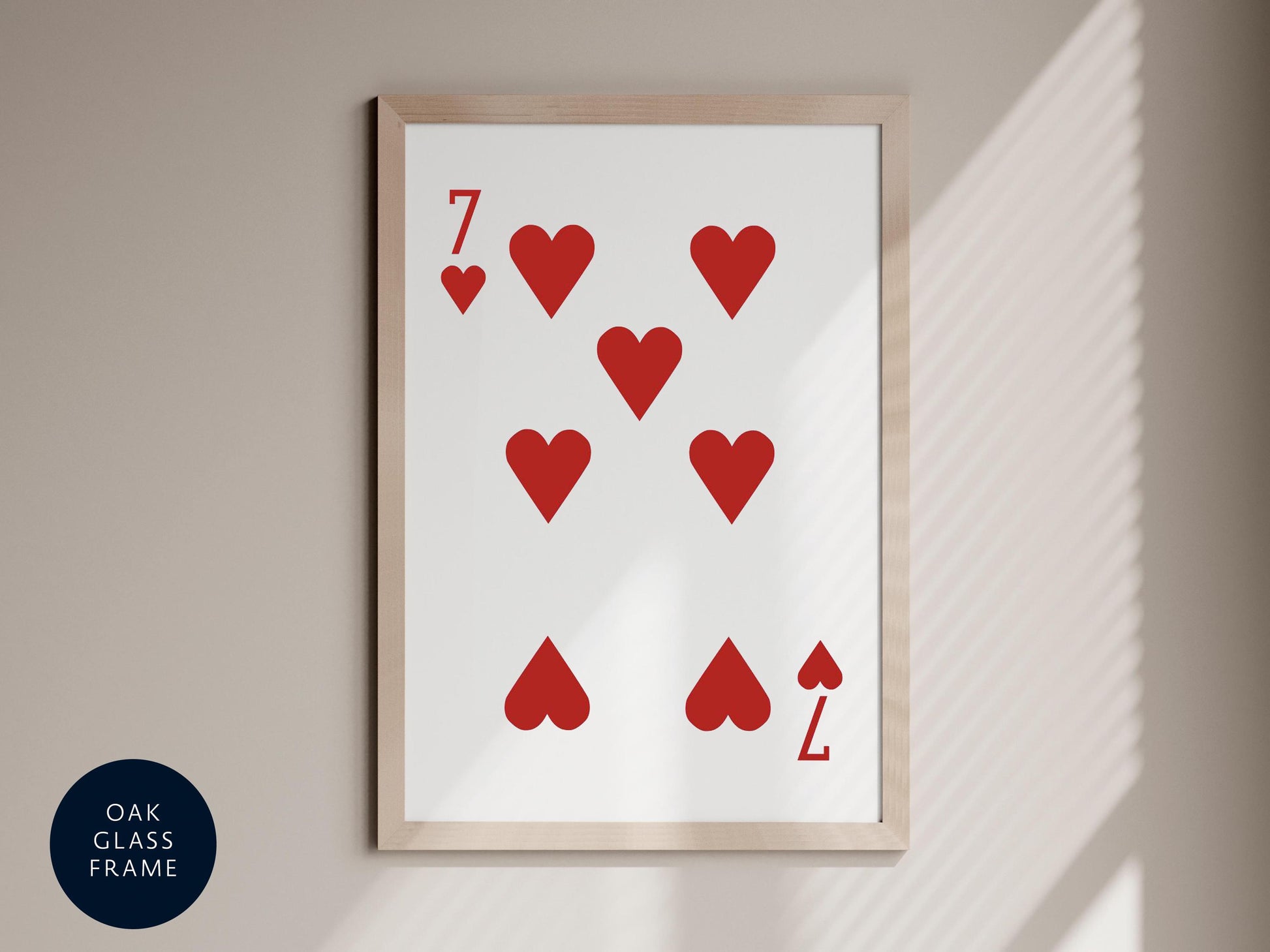 a framed print of a playing card with the number 7 and hearts on it, hanging on a wall.