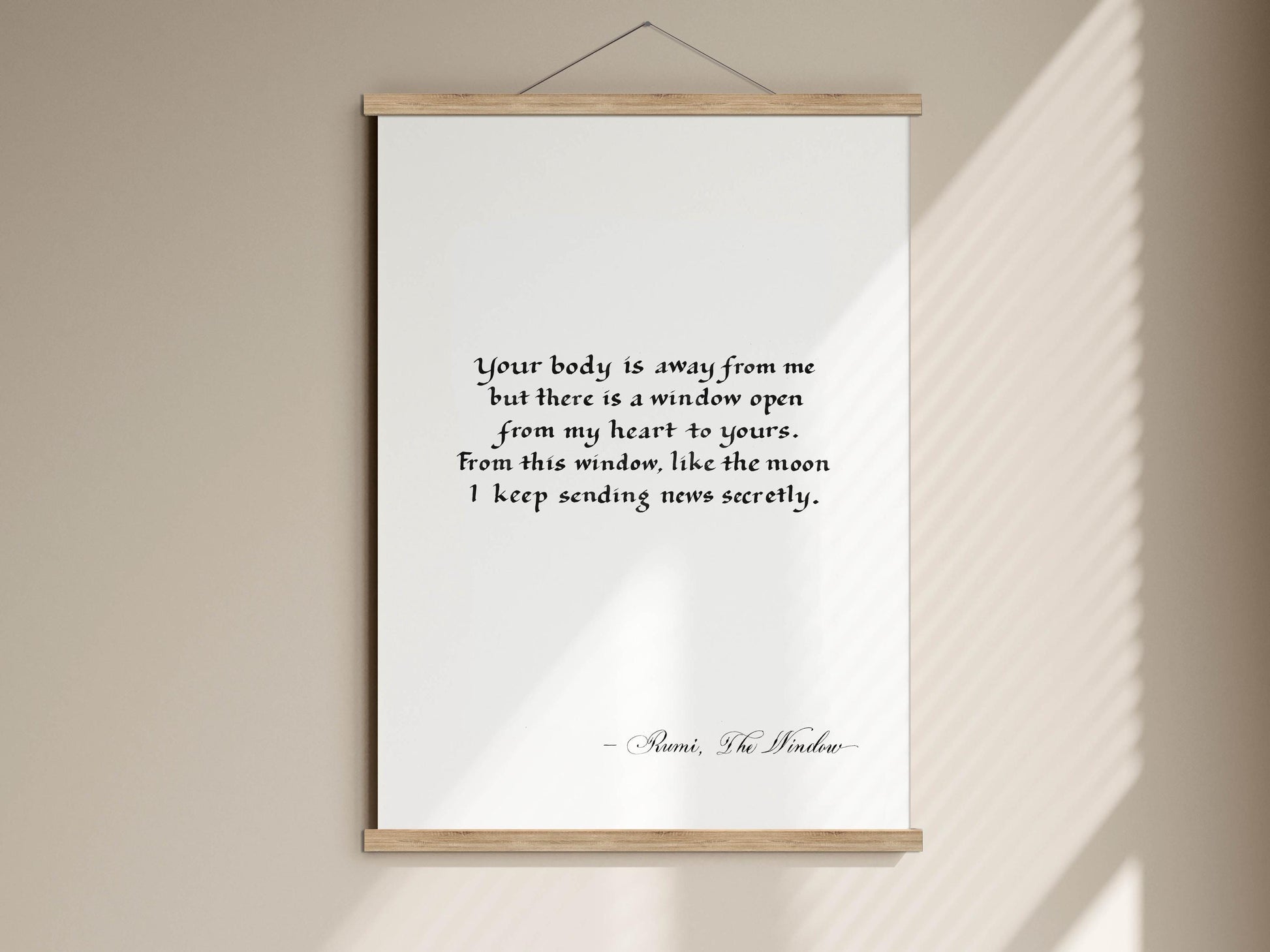 a quote on a white background, hanging on a wall. The quote is in black text and reads: "Your body is away from me but there is a window open from my heart to yours. From this window, like the moon I keep sending news securely."