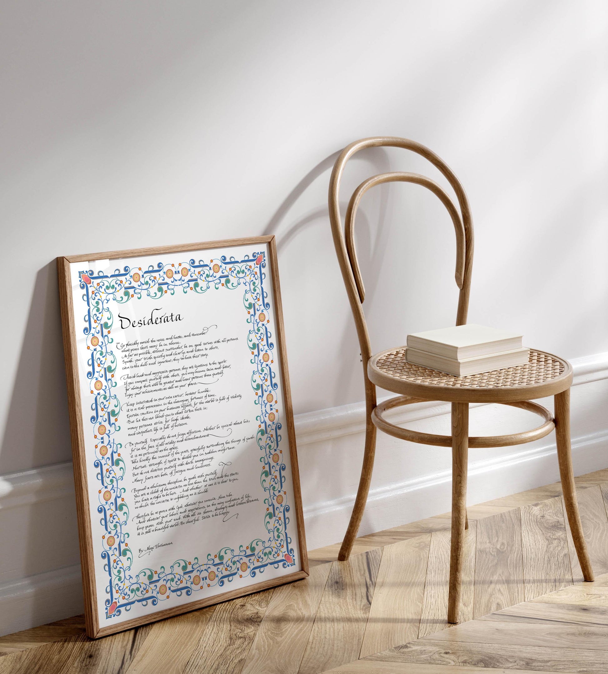a framed poem titled &quot;Dissiderta&quot; leaning against a white wall, with a wooden chair and a stack of books placed next to it on a wooden floor.