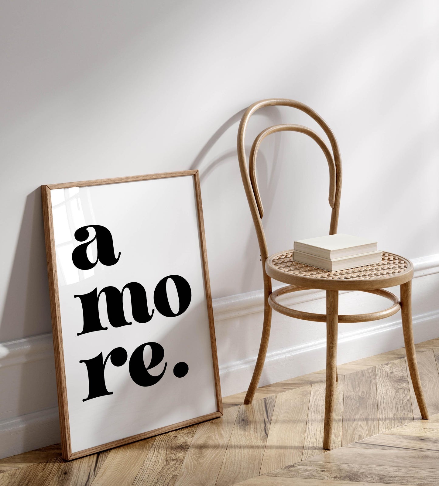a wooden chair with a book resting on it, positioned next to a framed poster with the text &quot;a more.&quot;