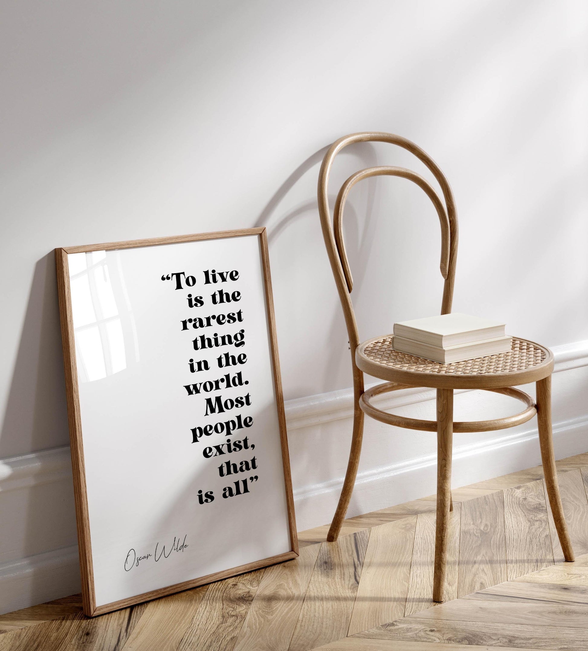 a wooden chair with a book on it, and there is a framed quote on the wall next to the chair.