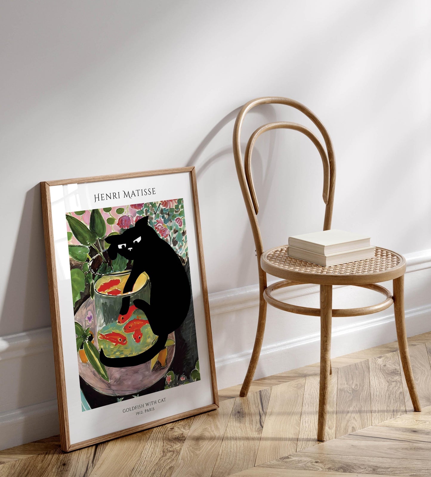 a framed painting of a black cat sitting in a fishbowl, with a wooden chair and a stack of books next to it.