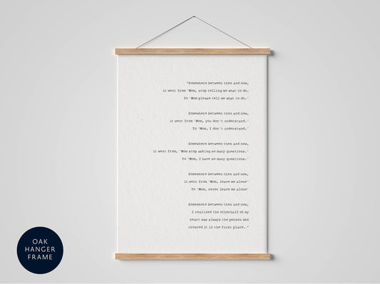 The image is a framed print of a poem titled &quot;Someplace between rain and sun.&quot; The poem is written in black text on a white background, and it is hanging on a wall.