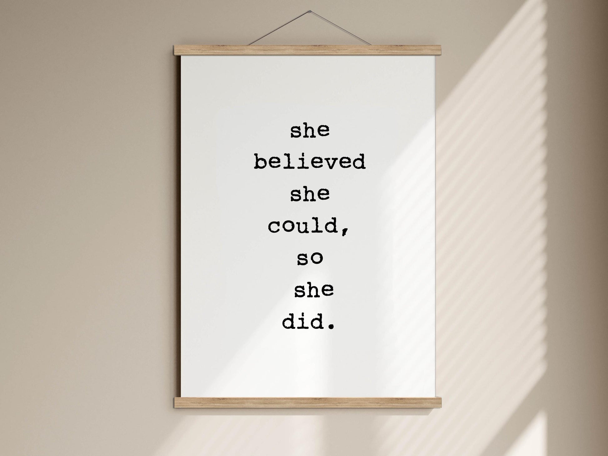 a motivational quote poster hanging on a wall, which reads &quot;she believed she could, so she did.&quot;