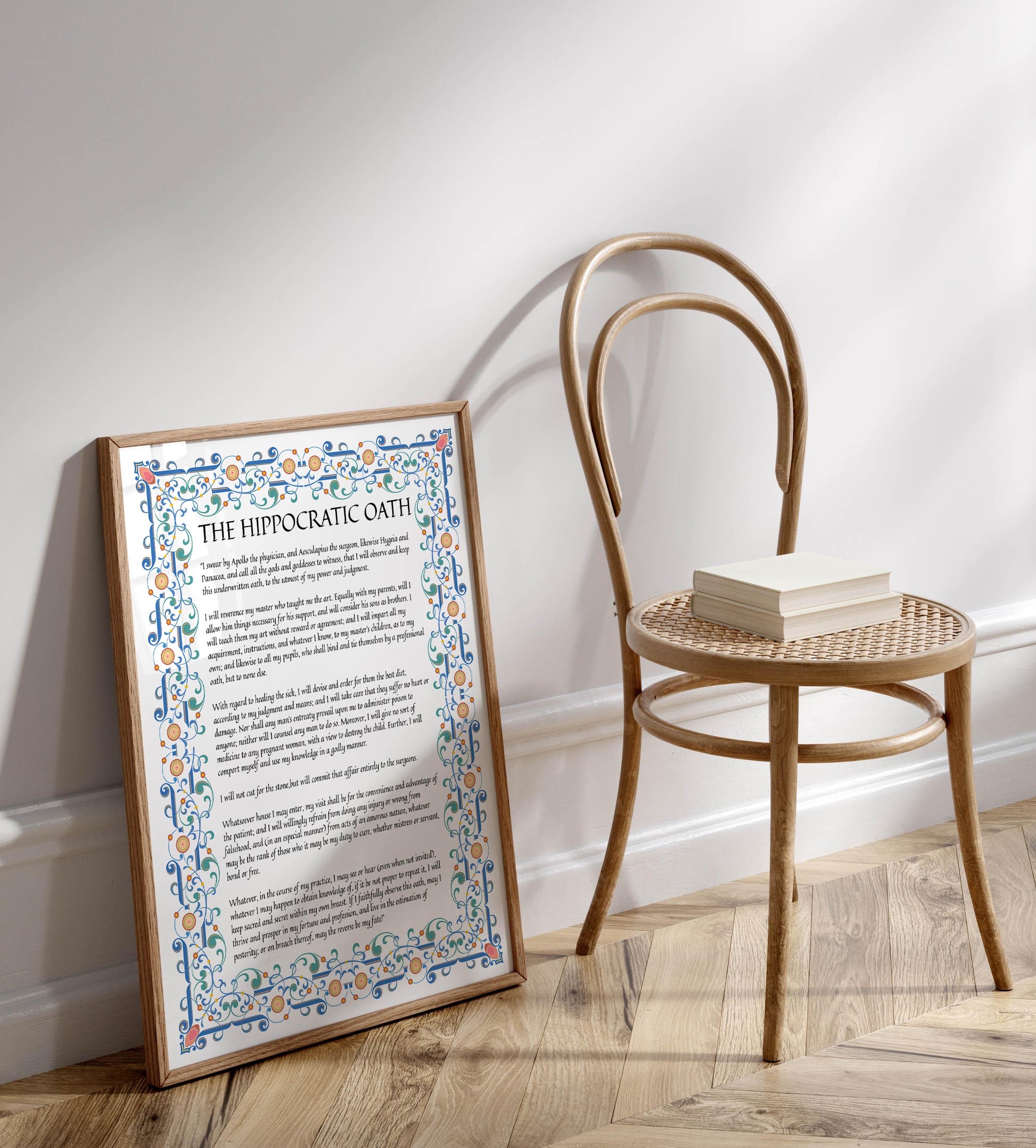 a framed poster with text and a decorative border, placed next to a wooden chair on a wooden floor.