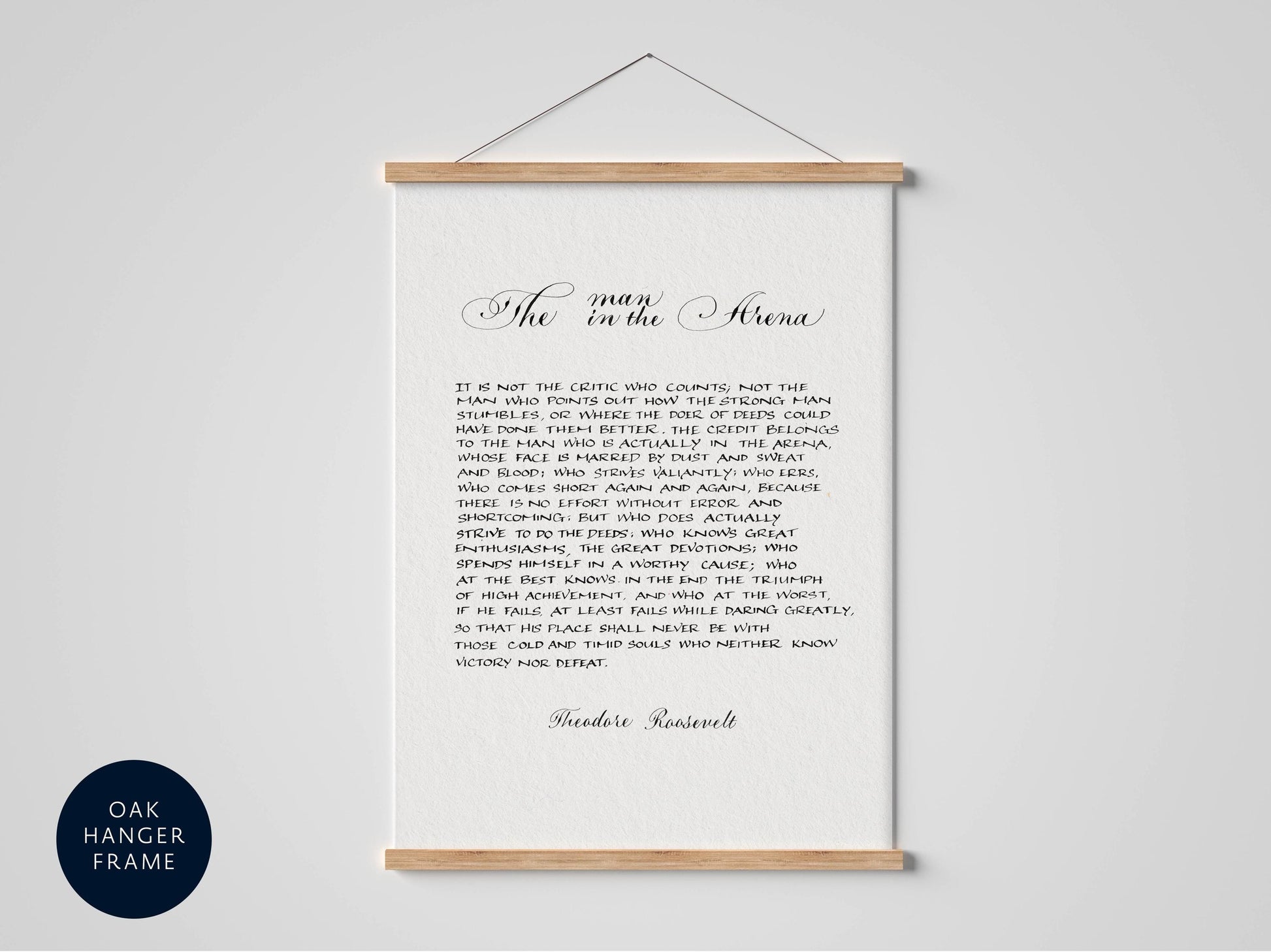 a framed text that reads &quot;The man in the arena&quot; and is written in cursive. The text is framed by a wooden border and is set against a white background.
