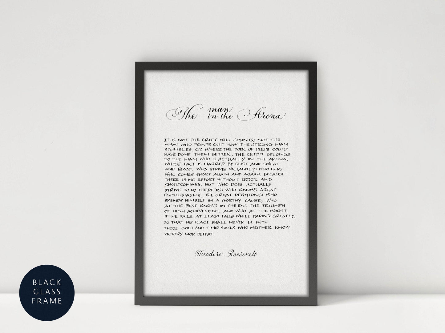 a quote by Theodore Roosevelt, a famous American president, which is framed and displayed in a black frame on a white wall.