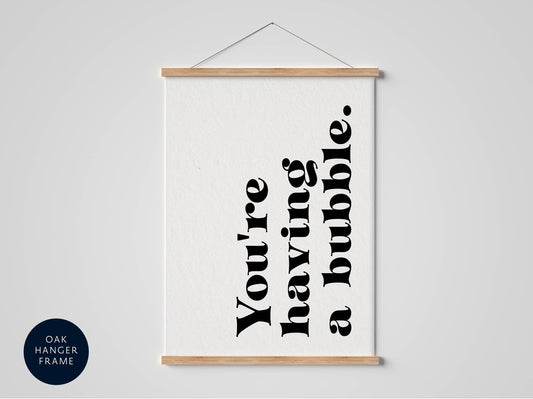 A white poster with black text that reads &quot;You&#39;re having a bubble&quot; hanging on a wall.