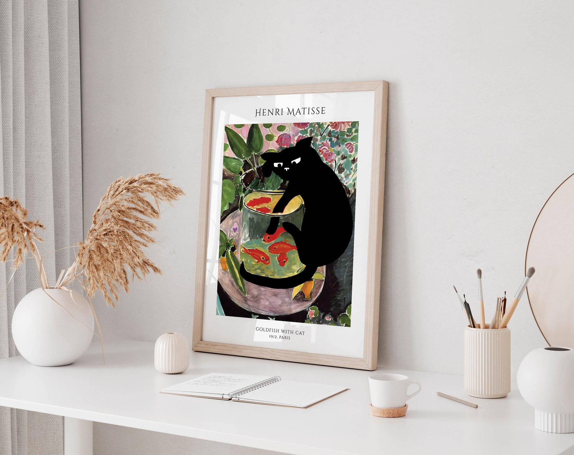 a framed painting of a black cat sitting in a fish bowl, surrounded by various objects such as a vase, a notebook, and a cup.