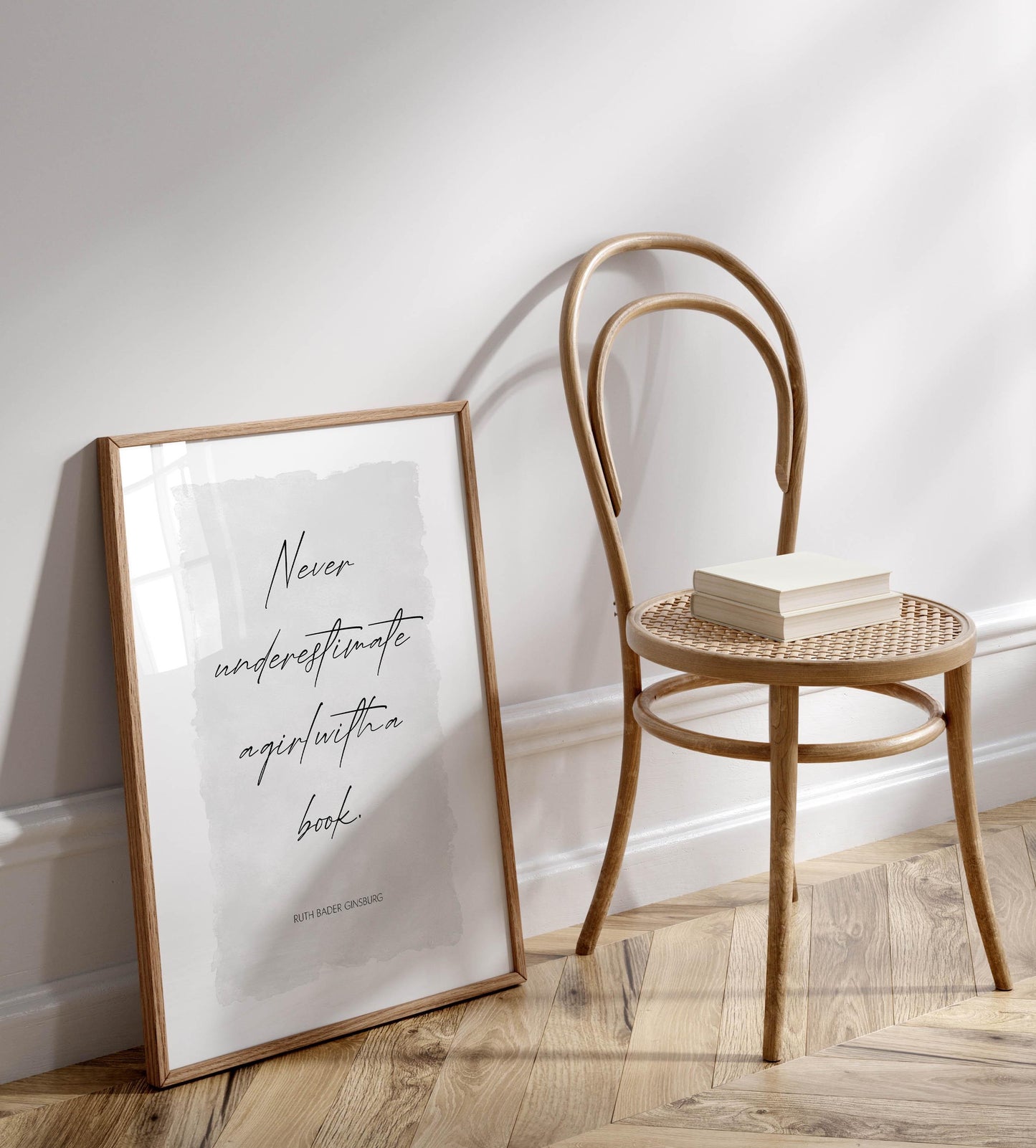 a wooden chair with a book resting on it, positioned next to a framed quote that reads &quot;Never underestimate agirlutica book.&quot;