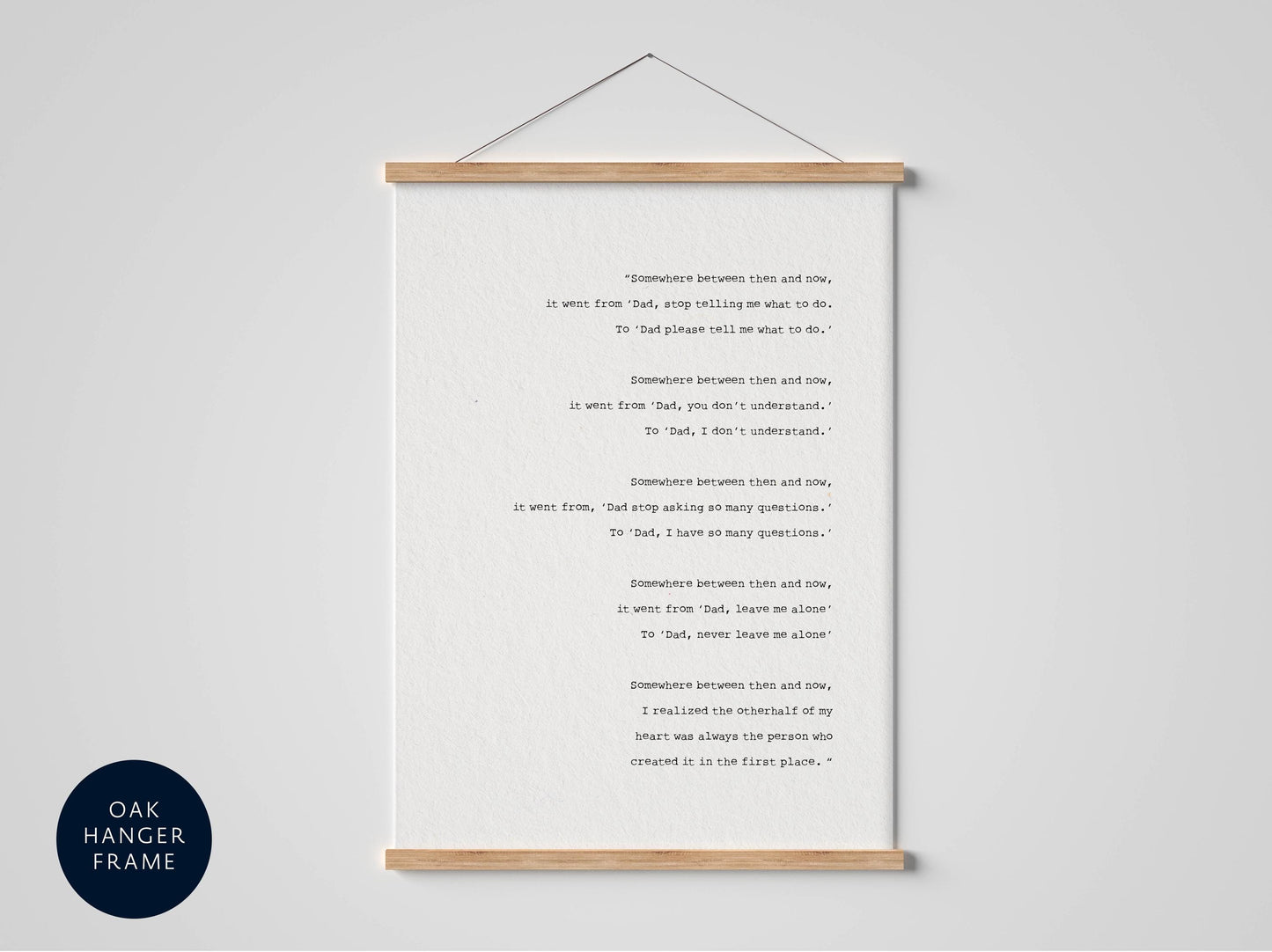 The image is a framed print of a poem titled &quot;Somebody between rain and sun.&quot; The poem is written in black text on a white background, and it is hung on a wall.