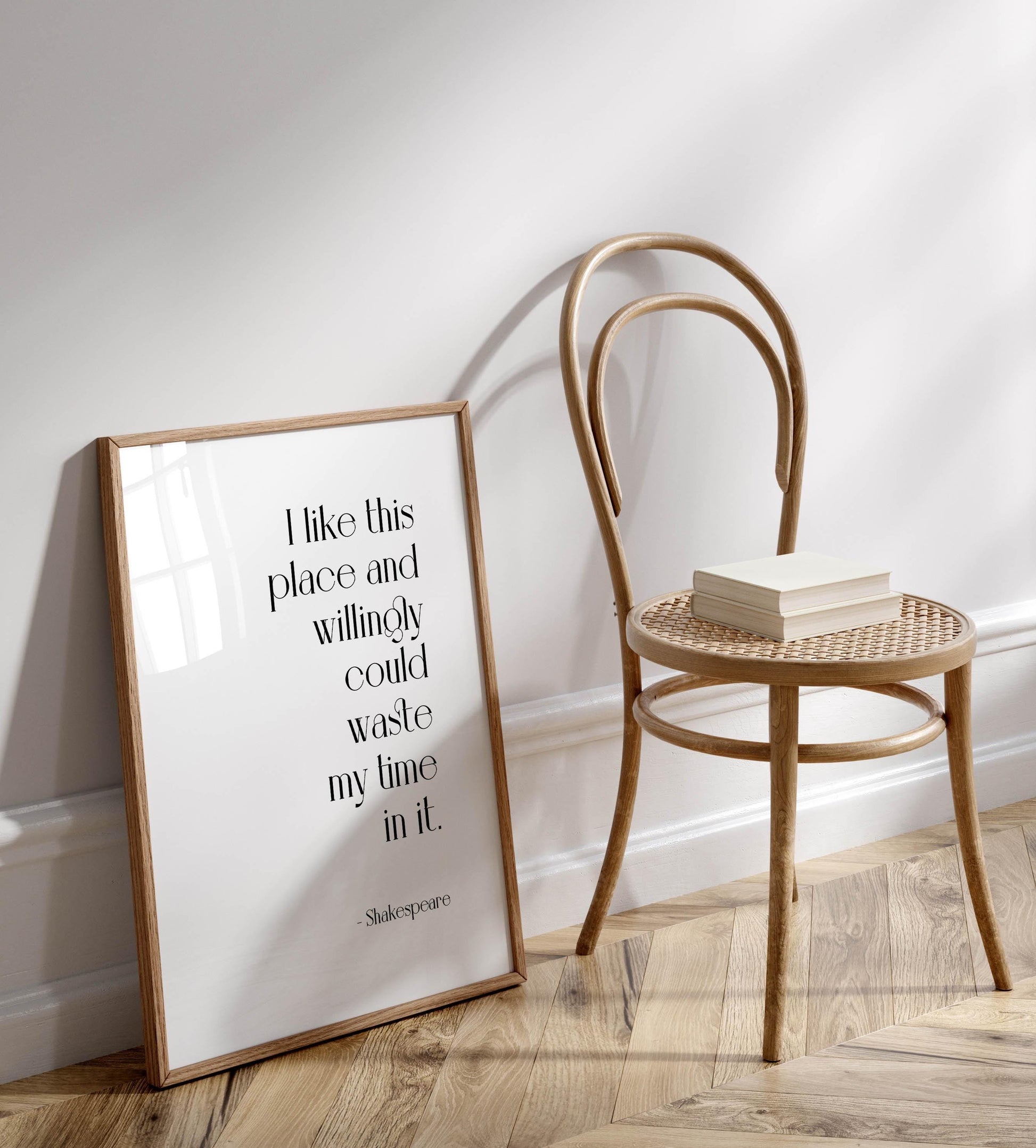 a wooden chair with a book resting on it, and a framed quote by William Shakespeare is displayed on the wall next to the chair.