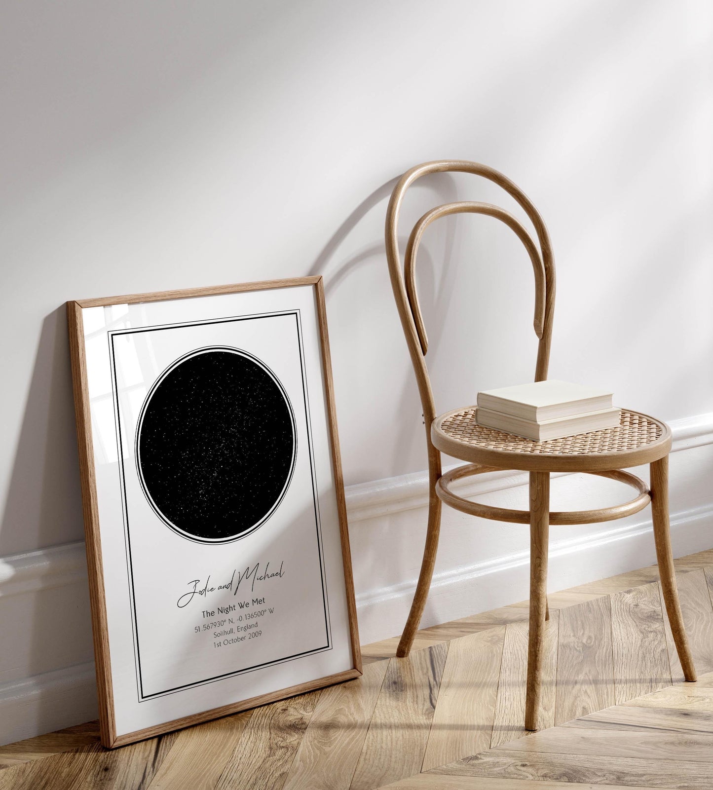 a wooden chair with a white book on it, placed next to a framed picture of a starry night sky.