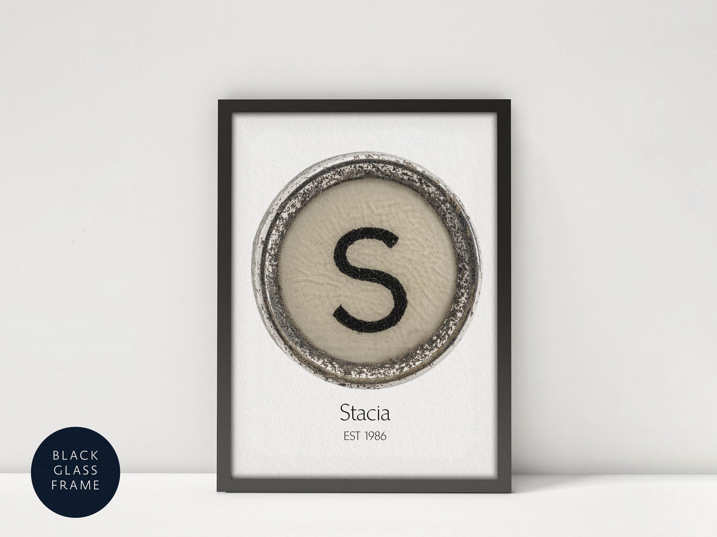 a framed print with a circular design containing the letter &#39;S&#39; in the center, and the text &quot;Stacia EST 1986&quot; below the design.