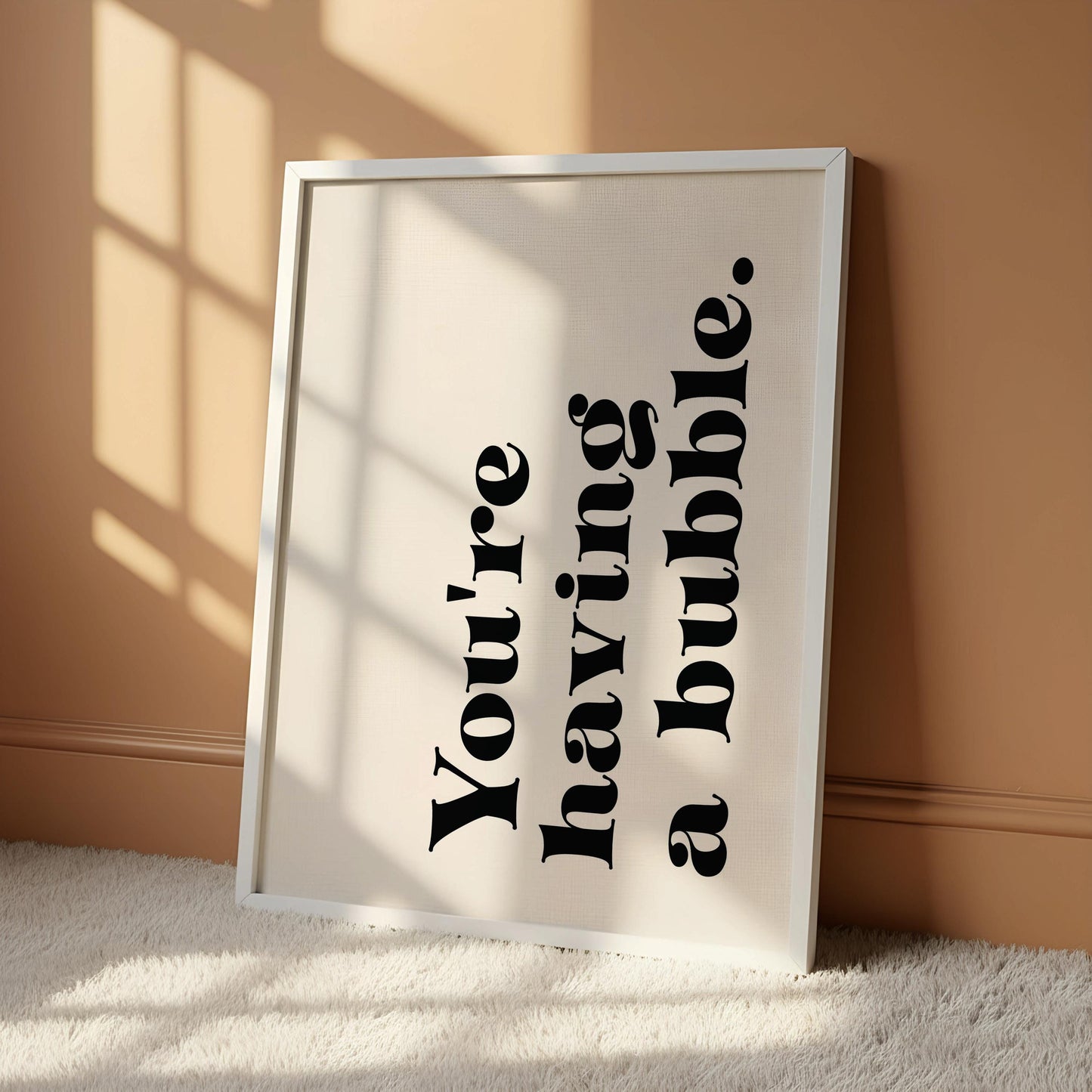 A white poster with black text that reads "You're having a bubble" hanging on a wall.
