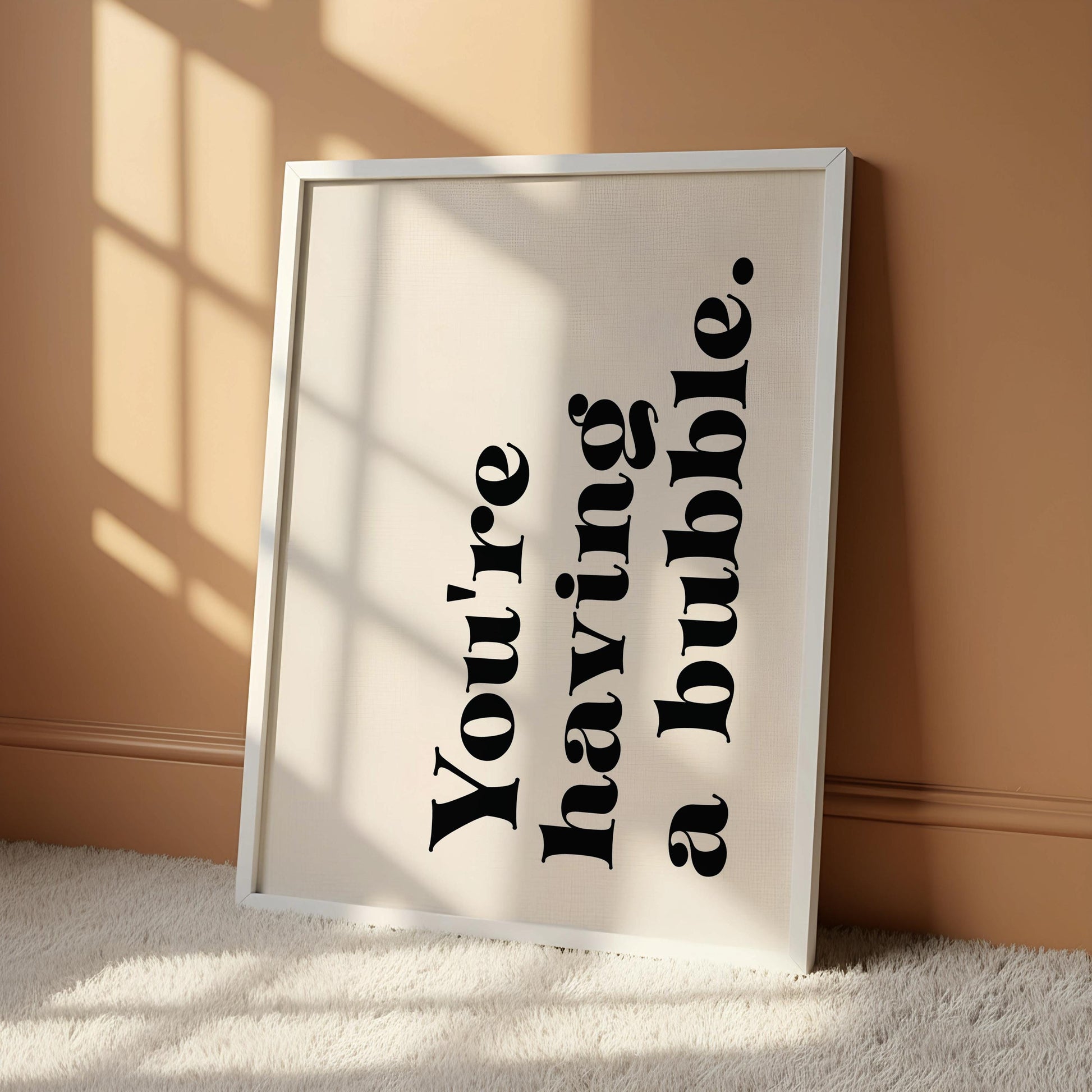 A white poster with black text that reads "You're having a bubble" hanging on a wall.