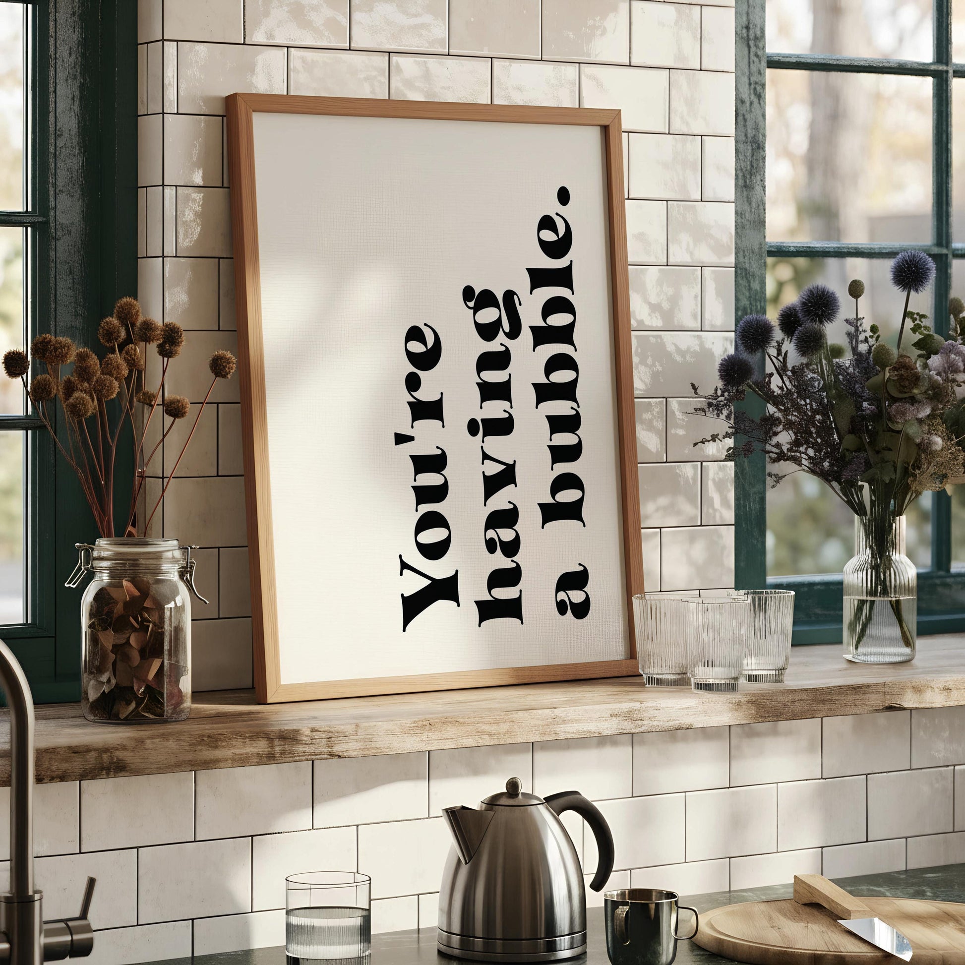 a white wall with a framed quote that reads "You're having a bubble" in black text. Next to the wall is a wooden chair with a stack of books on it.