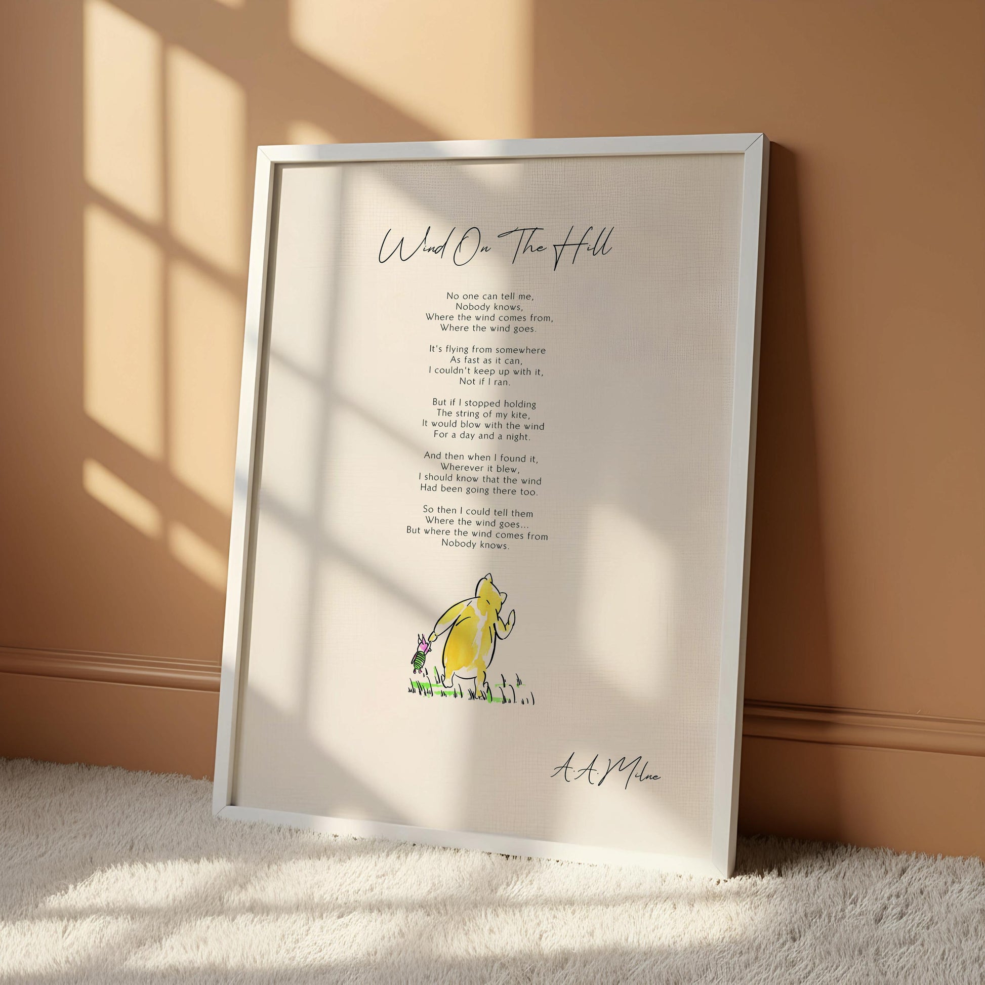 a framed print of a poem titled "Wind on the Hill" by A.A. Milne, accompanied by a small illustration of a yellow character.