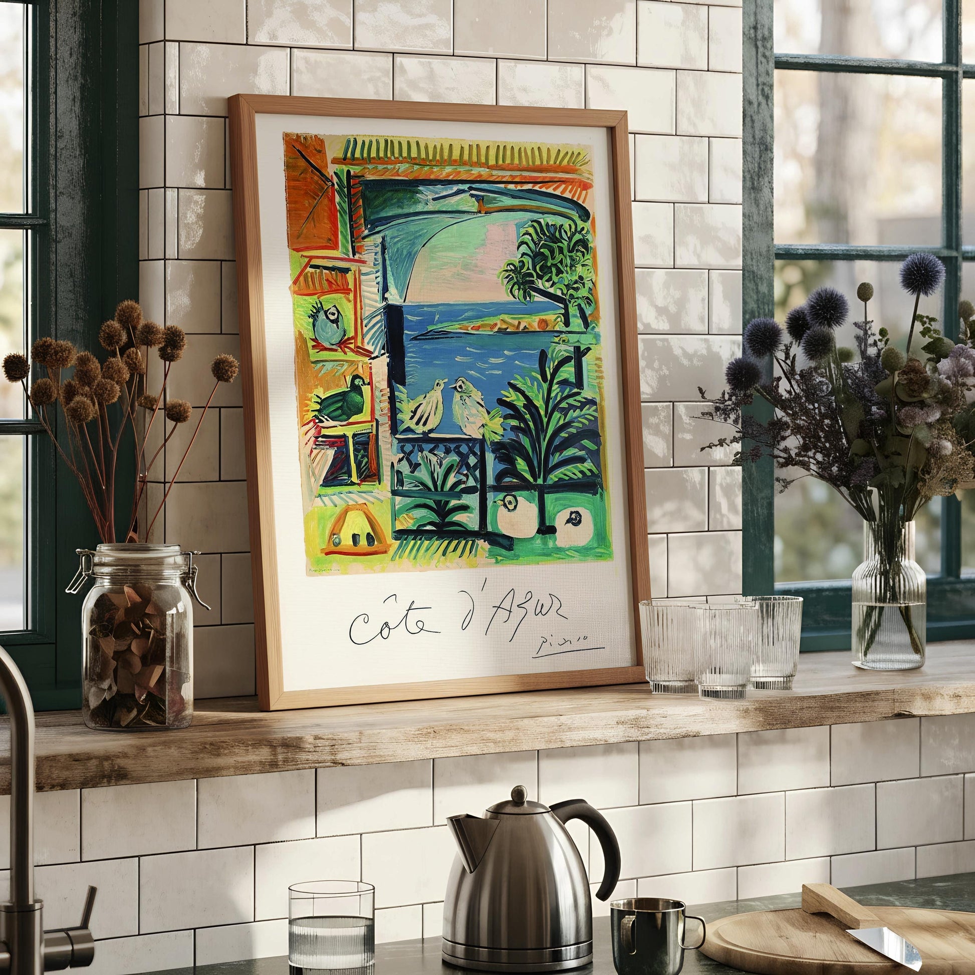 The image is a framed artwork depicting a colorful, abstract scene with various elements such as birds, palm trees, and a body of water.
