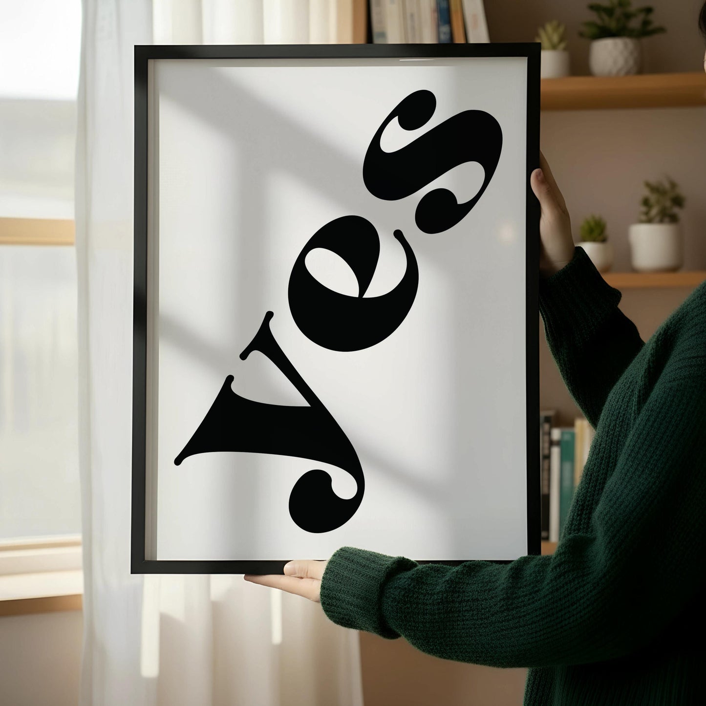 a wooden chair with a stack of books on it, placed against a white wall. There is a framed poster with the word "Yes" written on it, positioned on the floor next to the chair.
