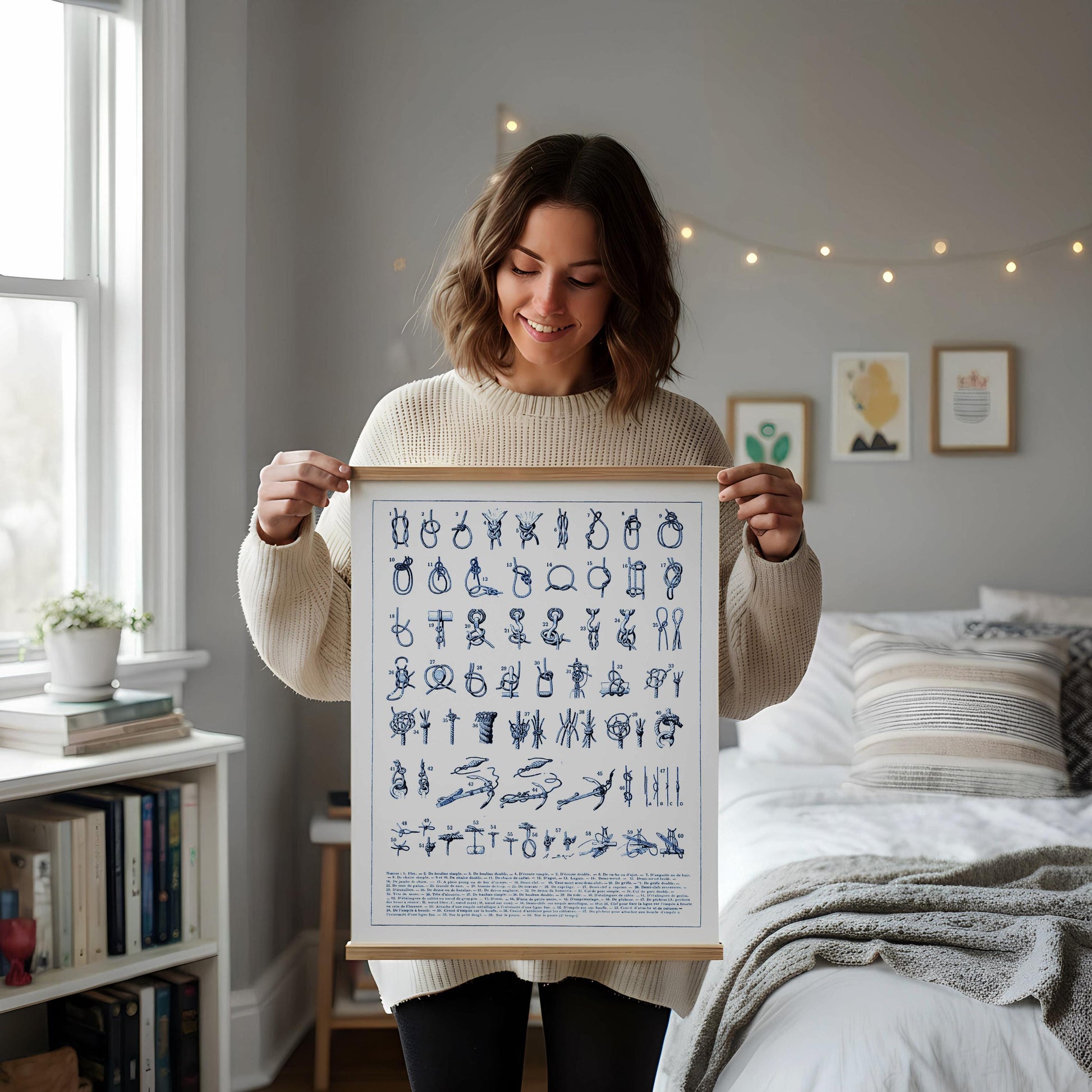 a framed poster with various illustrations and text, placed on a white desk with a notebook, a cup, and a vase of dried flowers.