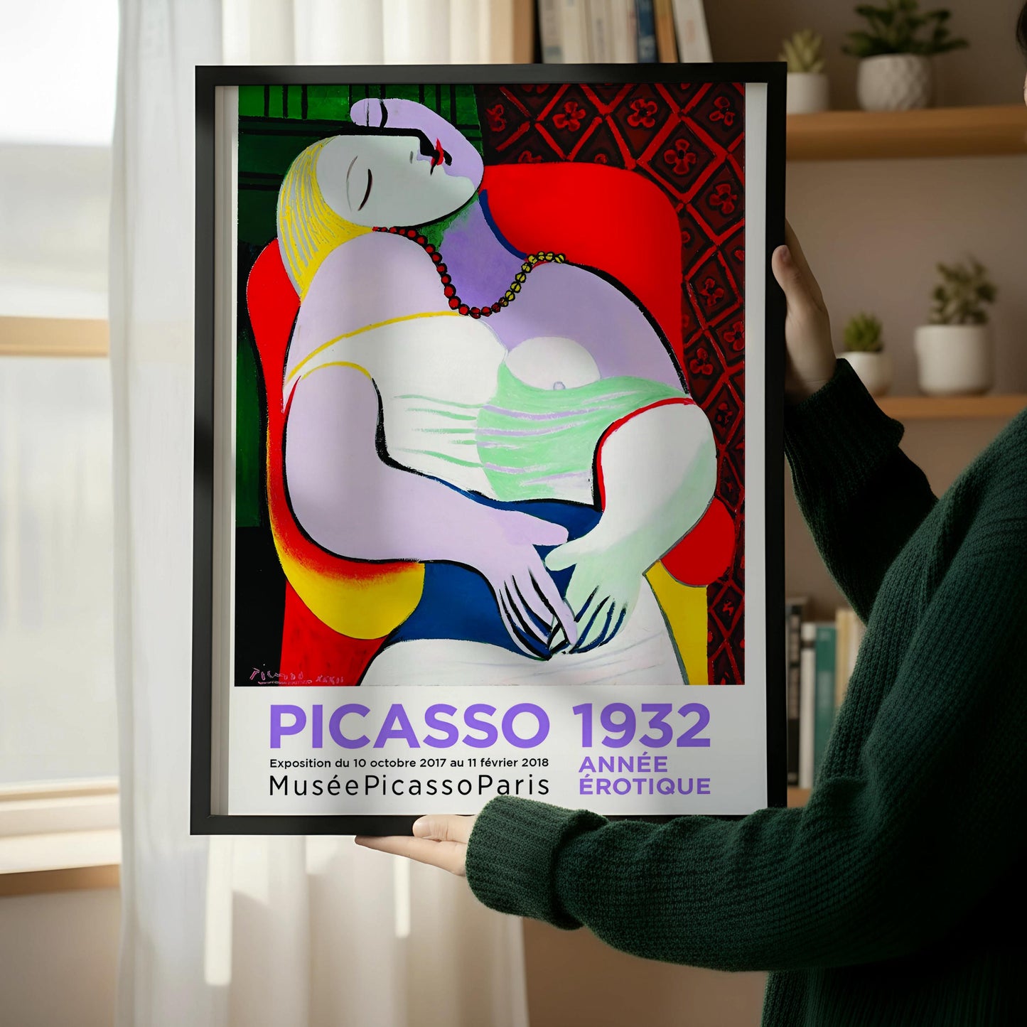 a colorful Picasso 1932 poster displayed on a wall next to a wooden chair.